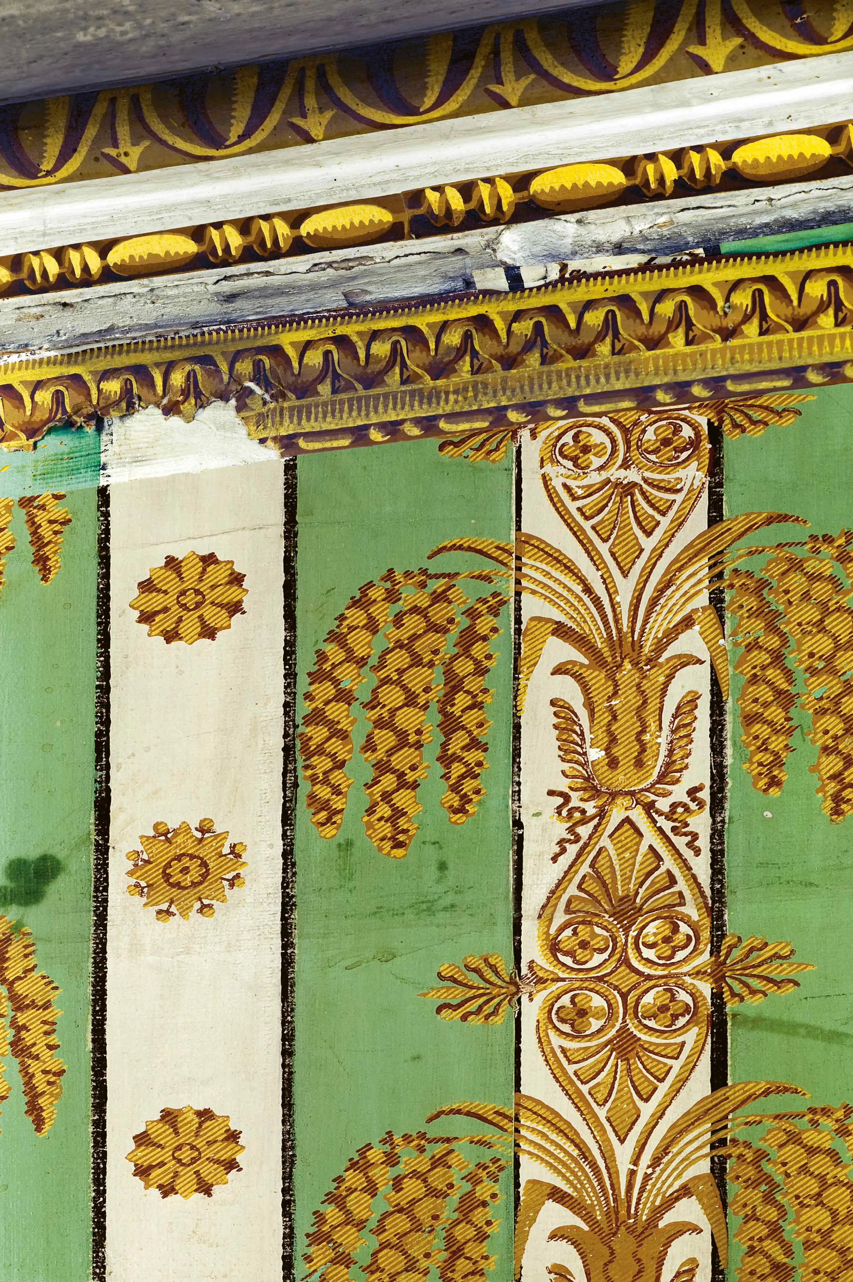 En vägg tapetserad med en tapet med vita och mintgröna lodräta, breda ränder. Tapeten är dekorerad med gul- och guldfärgade mönster.