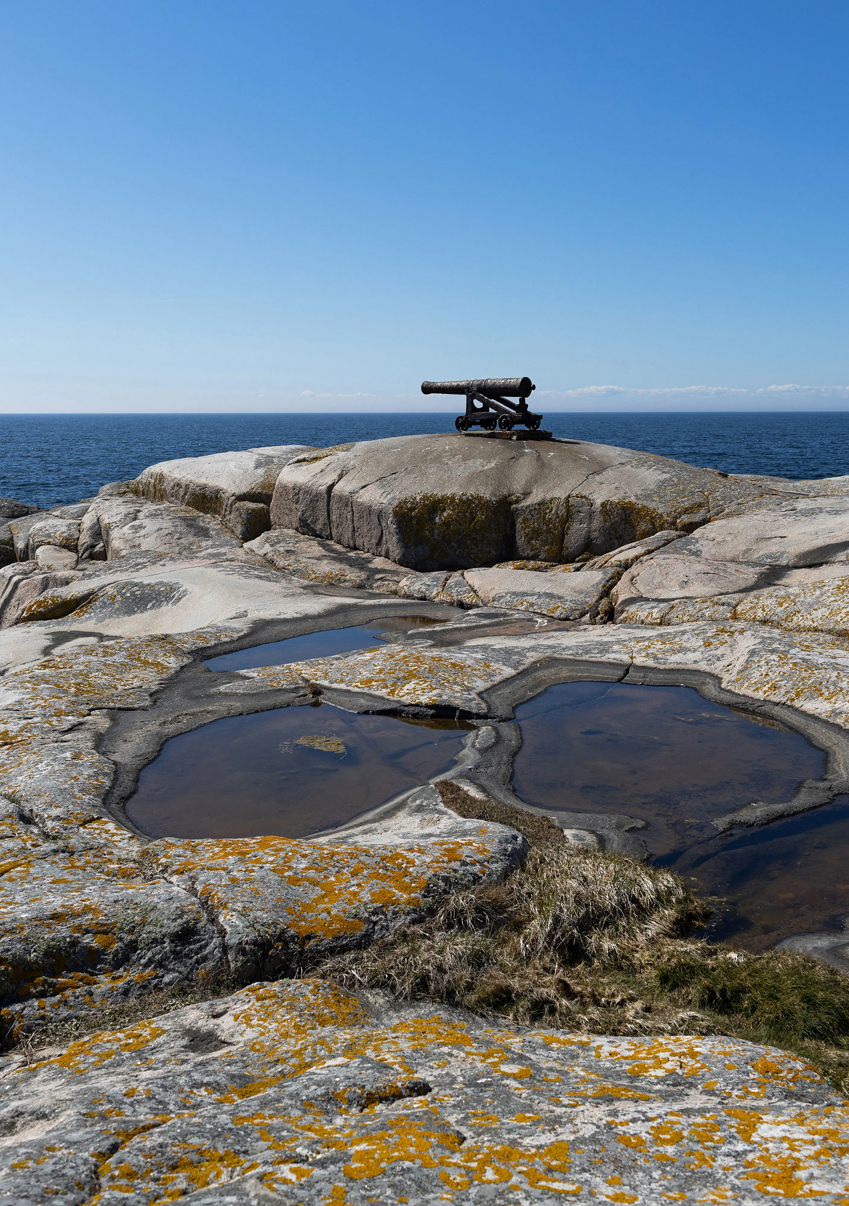 Klippor med kanon och vy över havet.