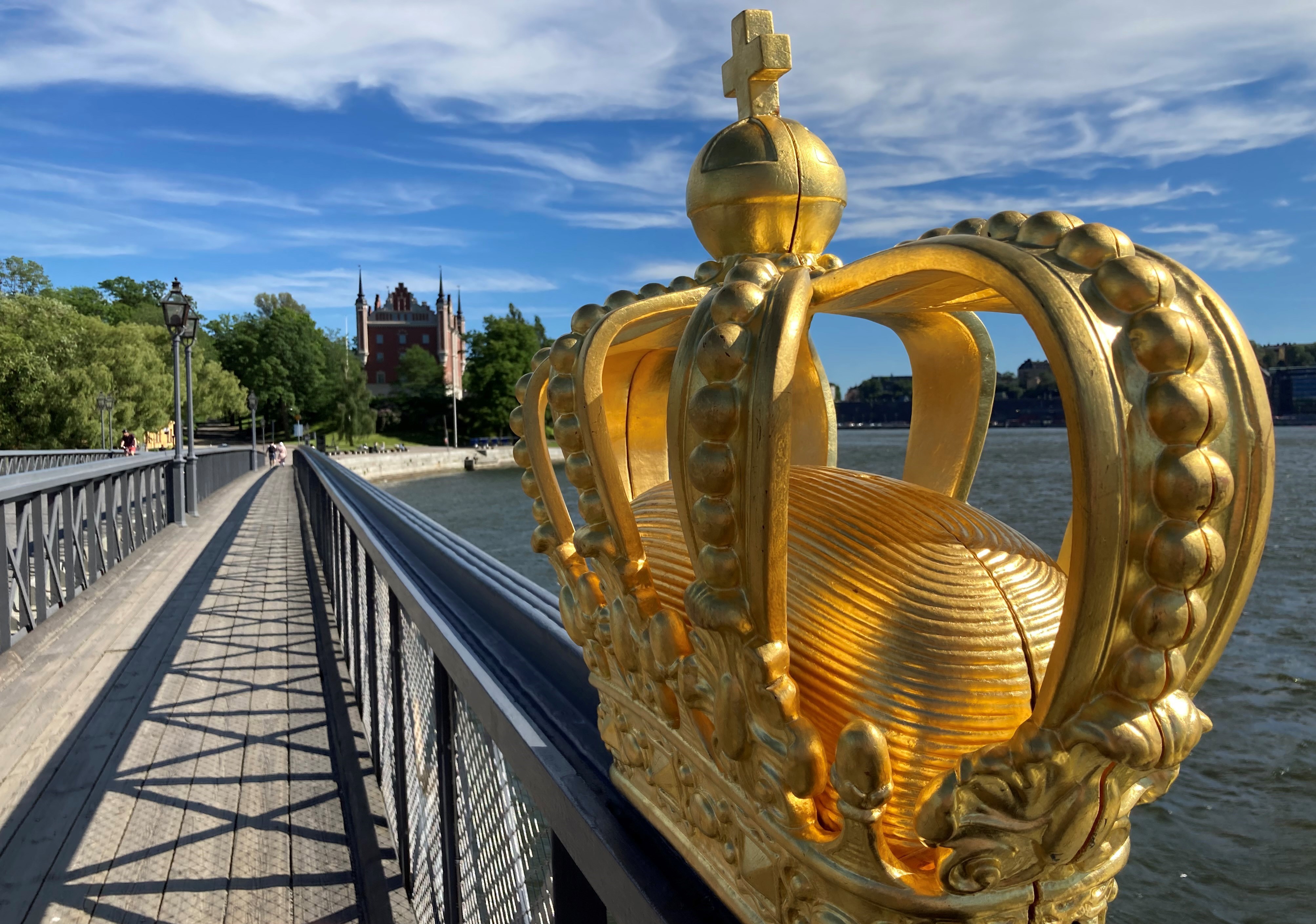 Skeppsholmsbron. Gjutjärnsbro med gångbana i trä. Vy mot Skeppsholmen. I förgrunden en förgylld krona som pryder broräcket.