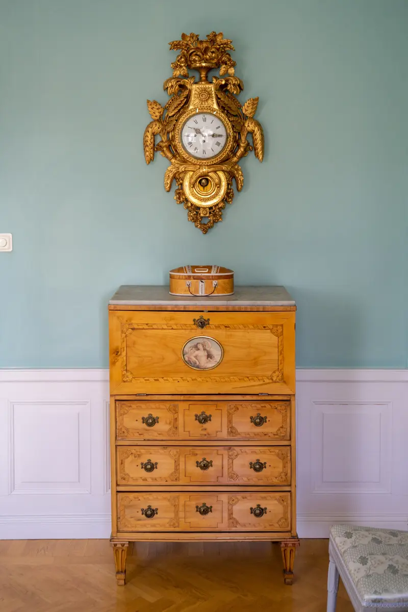 Rikt utsmyckad byrå av trä och en påkostad väggklocka med förgyllda detaljer.