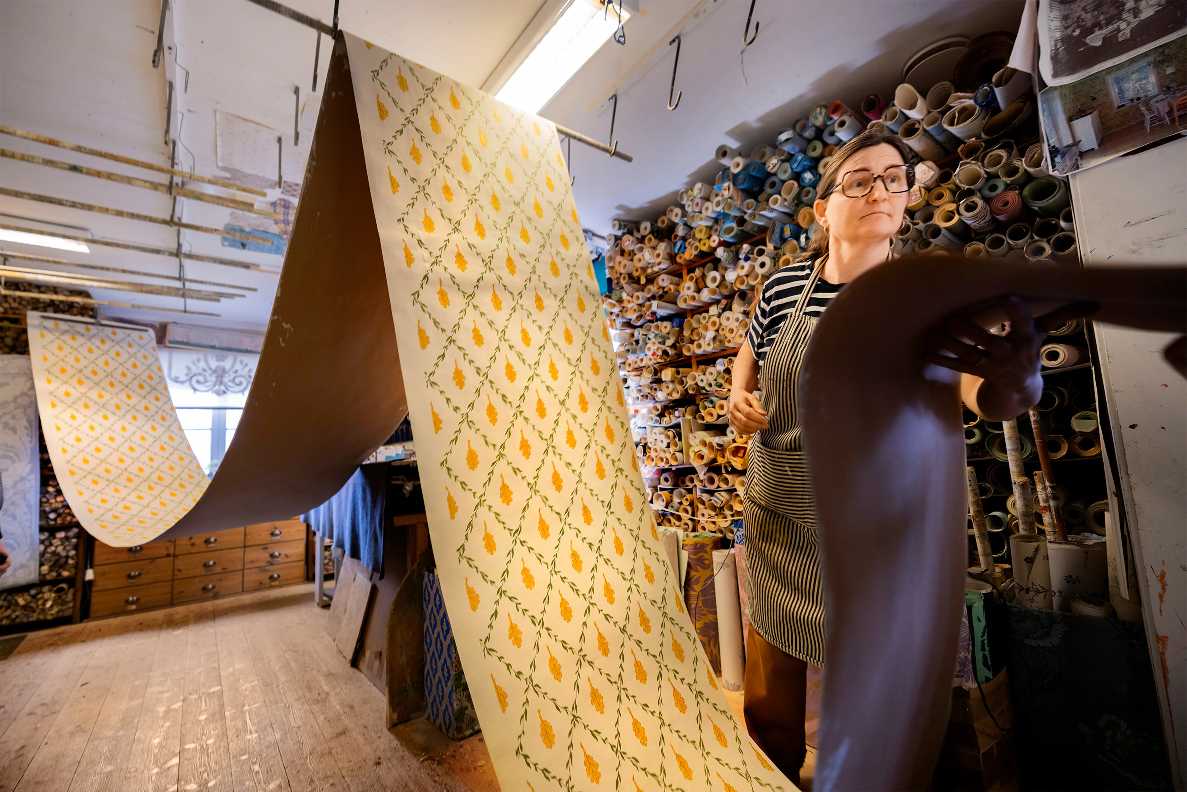 Tapetvåd på tork i tak och kvinna som håller i ena delen.