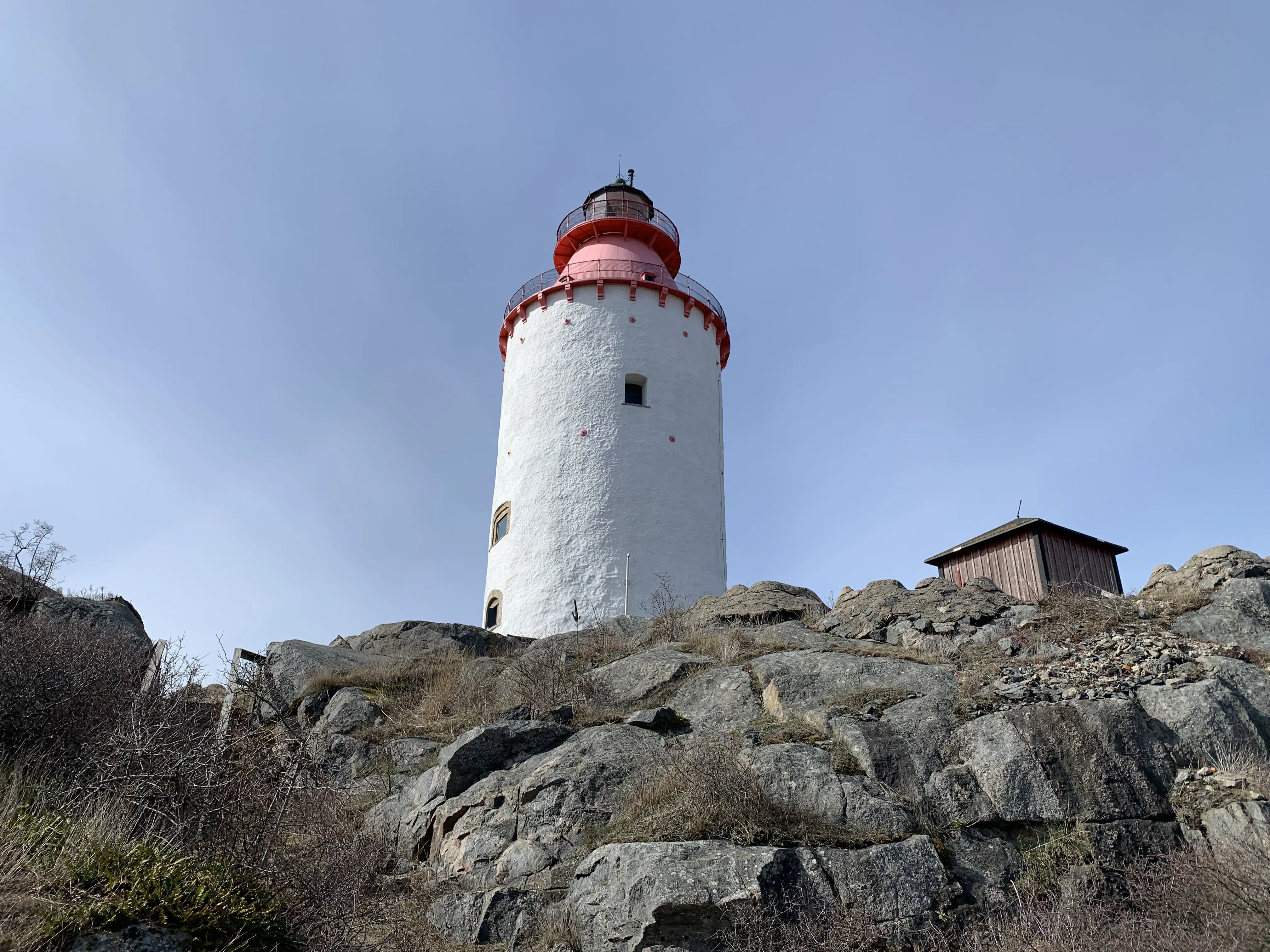 Landsorts fyr på Öja. Ett runt vitt fyrtorn med konisk plåt-topp. Plåten är rödmålad och högst upp sitter lanterninen.