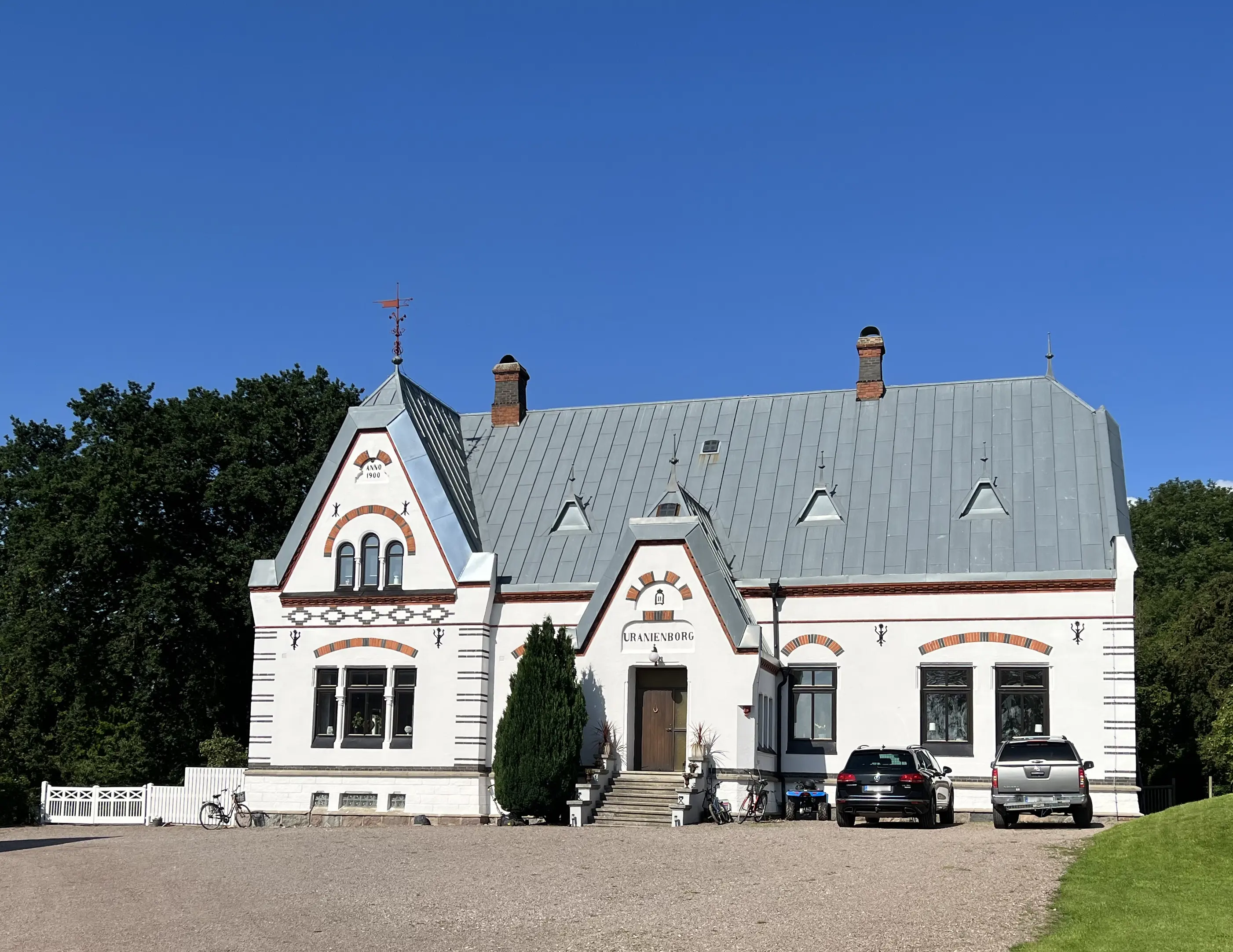Uranienborg. Vitputsat bostadshus med grått plåt-tak. Fasaden är dekorerad med ankarslut och brunt och svart tegel.