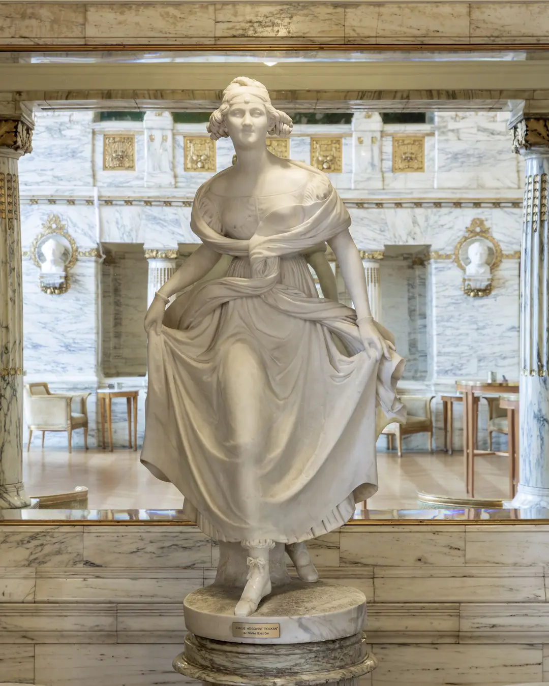 Marmorskulptur av en kvinna med klänning.