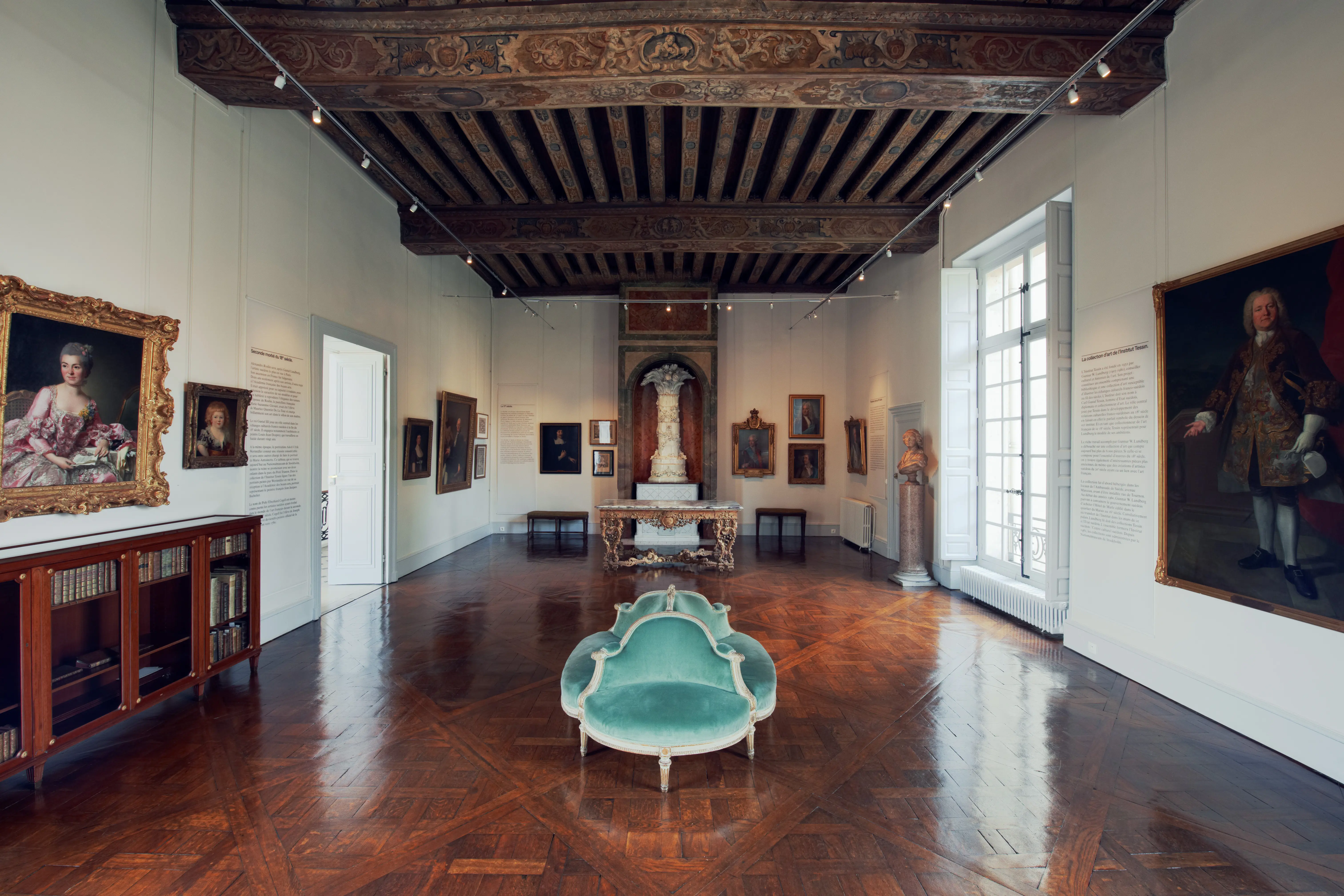 Svenska institutet i Paris, interiör. Utställningsrum med blankt, mönstrat trägolv och rejäla, målade takbjälkar. På väggarna hänger porträtt.