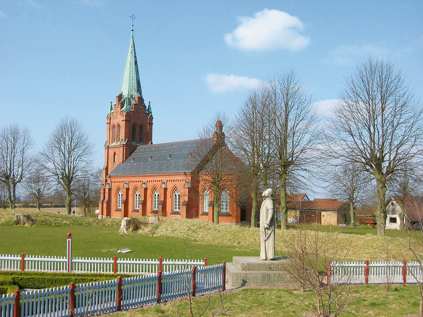 Allhelgonakyrkan sedd utifrån - en kyrka av tegel med ett torn som har ärgat koppartak.
