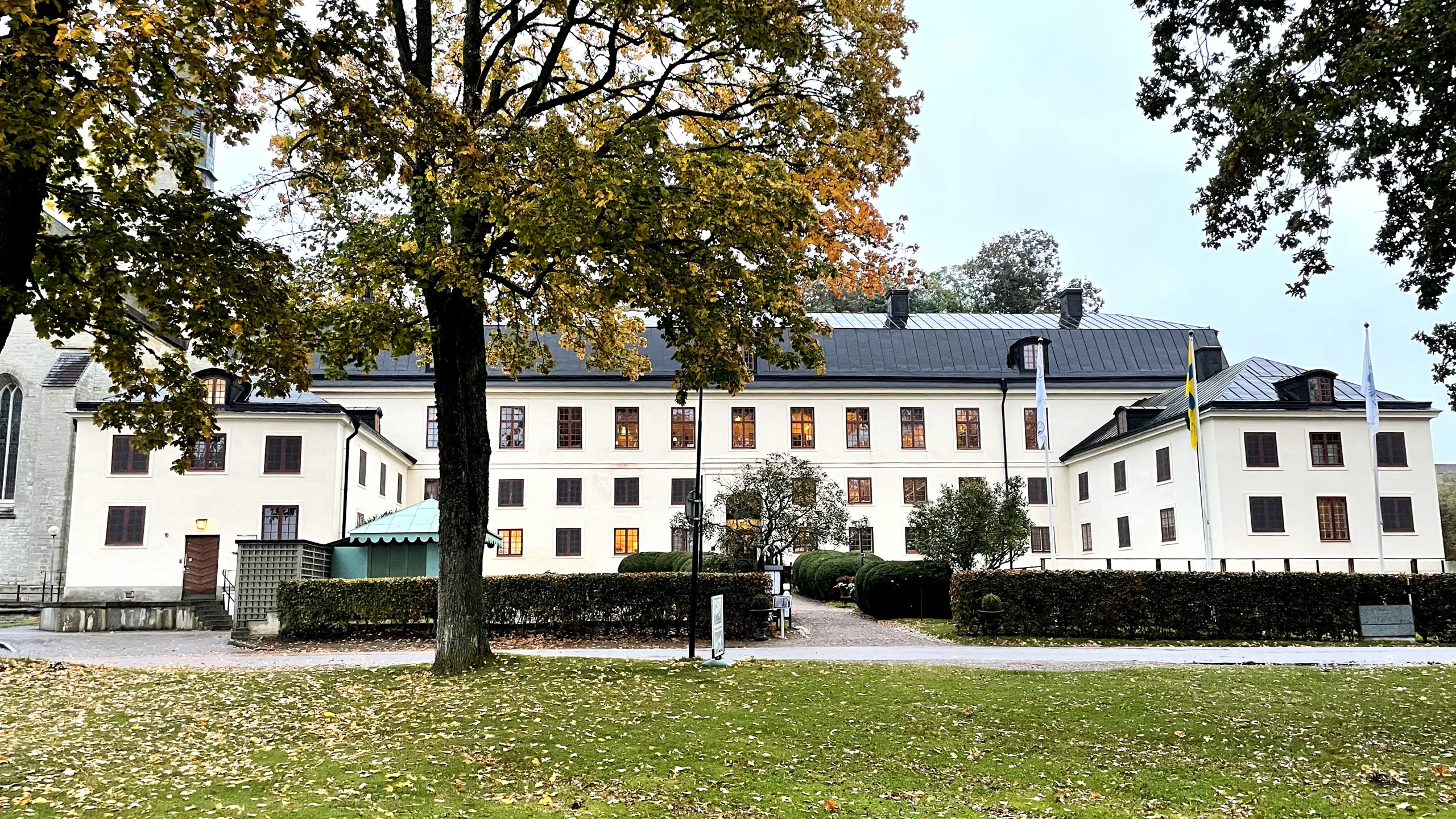 Munkklostret. En vit, enkel trevåningsbyggnad med något lägre flyglar. Höst.