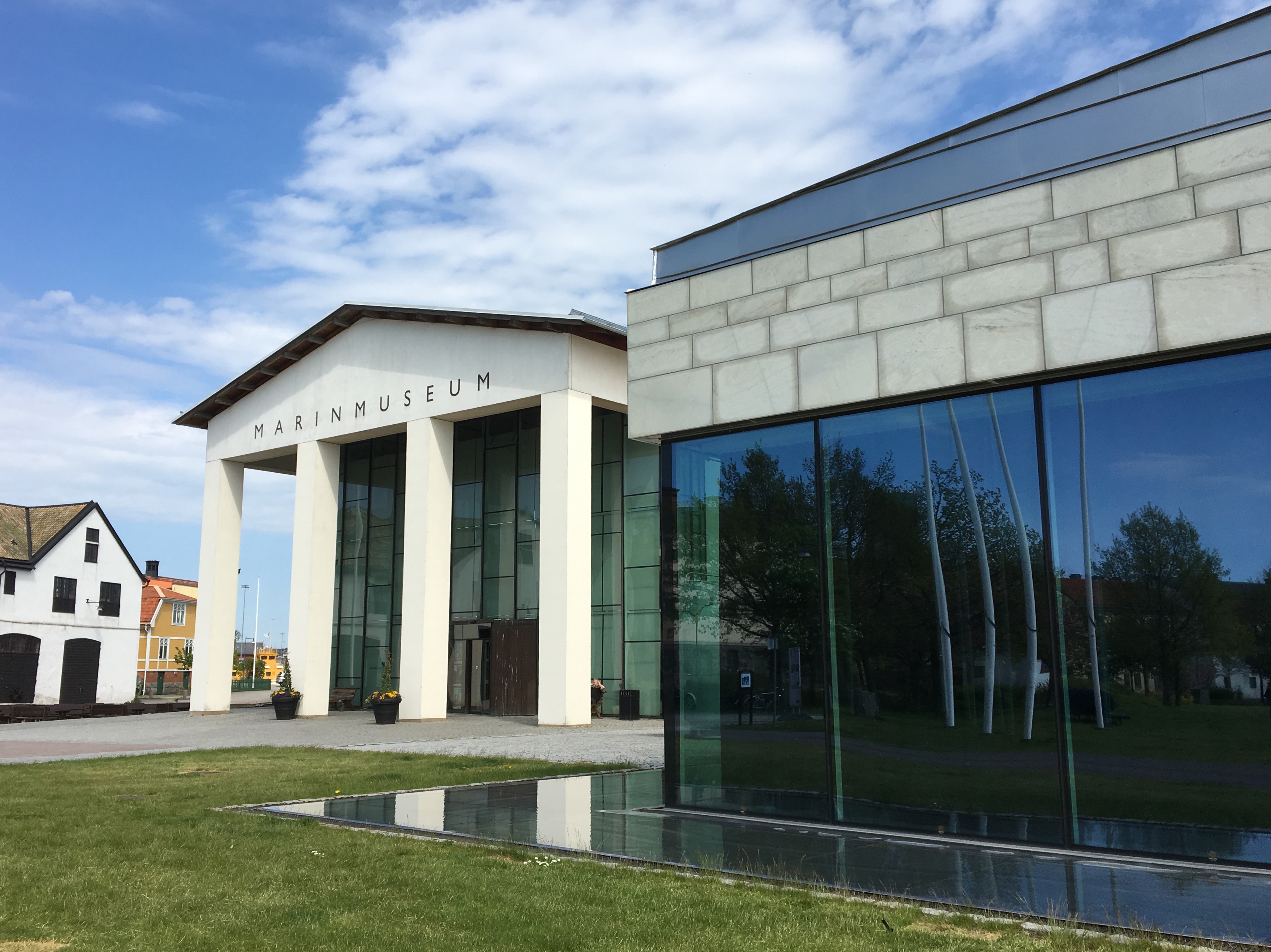 Marinmuseum och ubåtshallen i Karlskrona. Båda byggnaderna har vita fasader med stora glaspartier. Museets entré har fyra bastanta pelare.