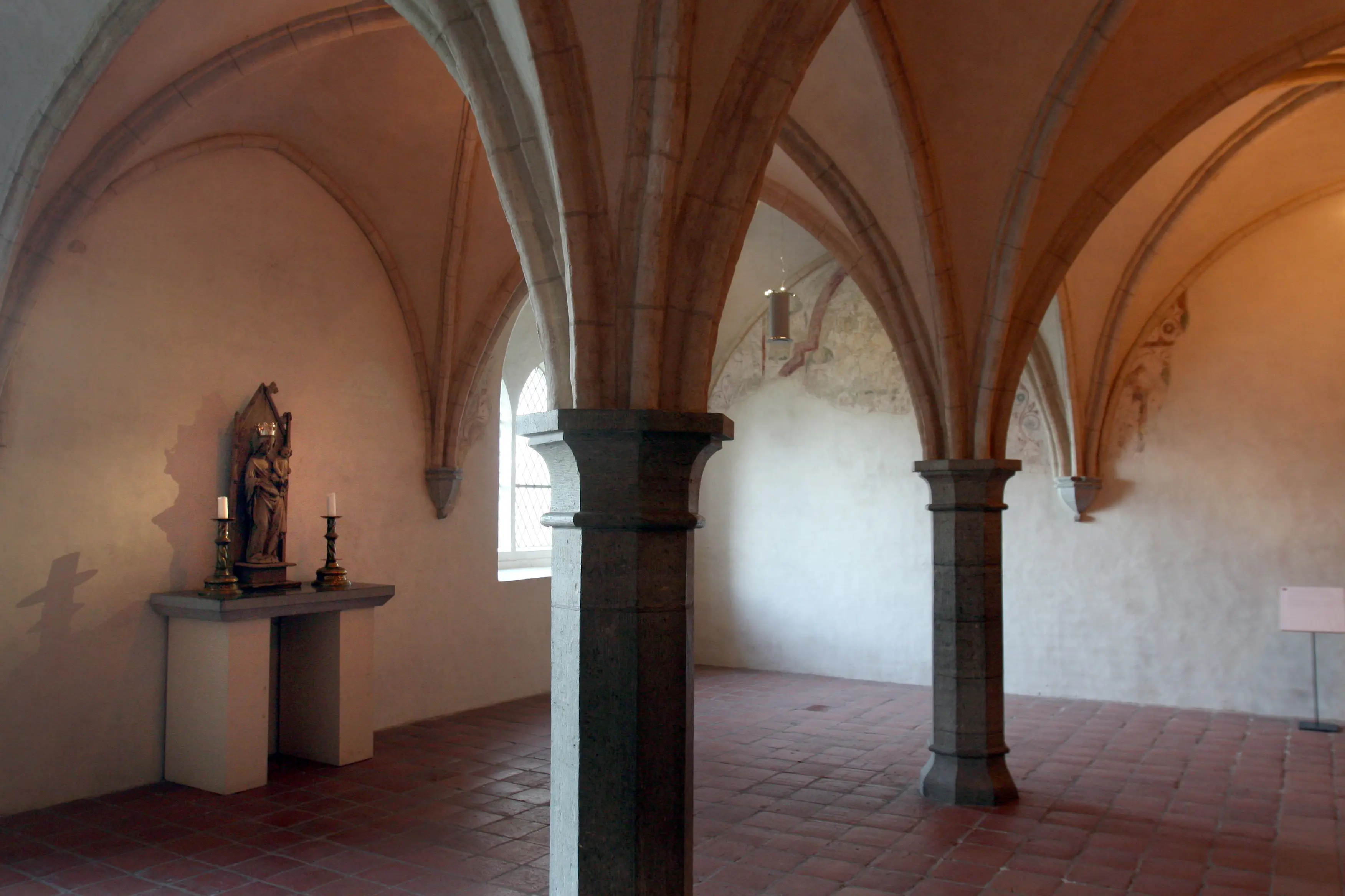 Interiör, nunneklostret i Vadstena. Bönerum med medeltida kryssvalv och pelare. Golvet är belagt med klinker. En madonnafigur står på ett litet altare.