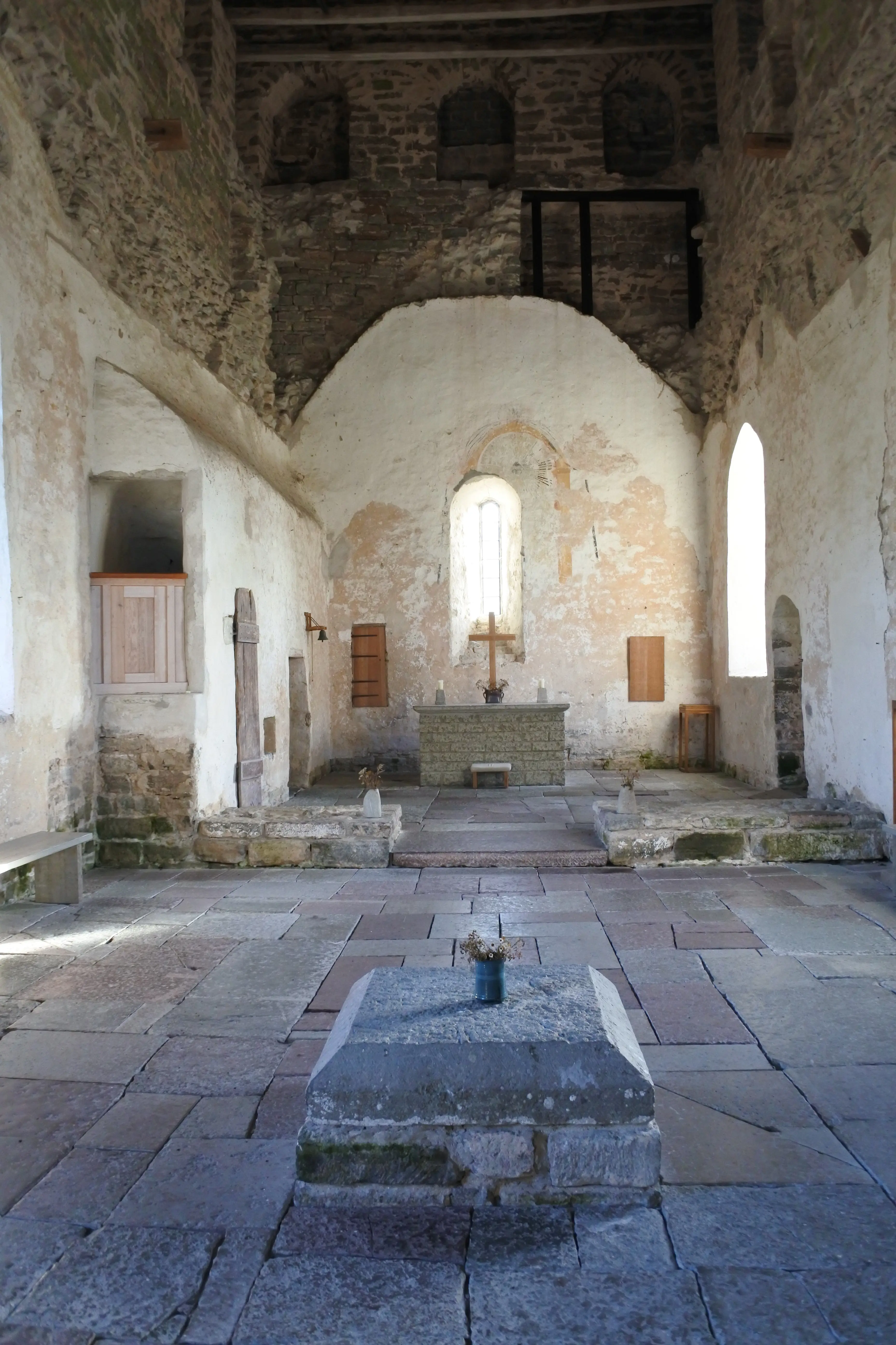 Interiör, Källa gamla kyrka. Golvet är av sten. Avgränsningen av väggarnas puts visar var det medeltida innertaket suttit.