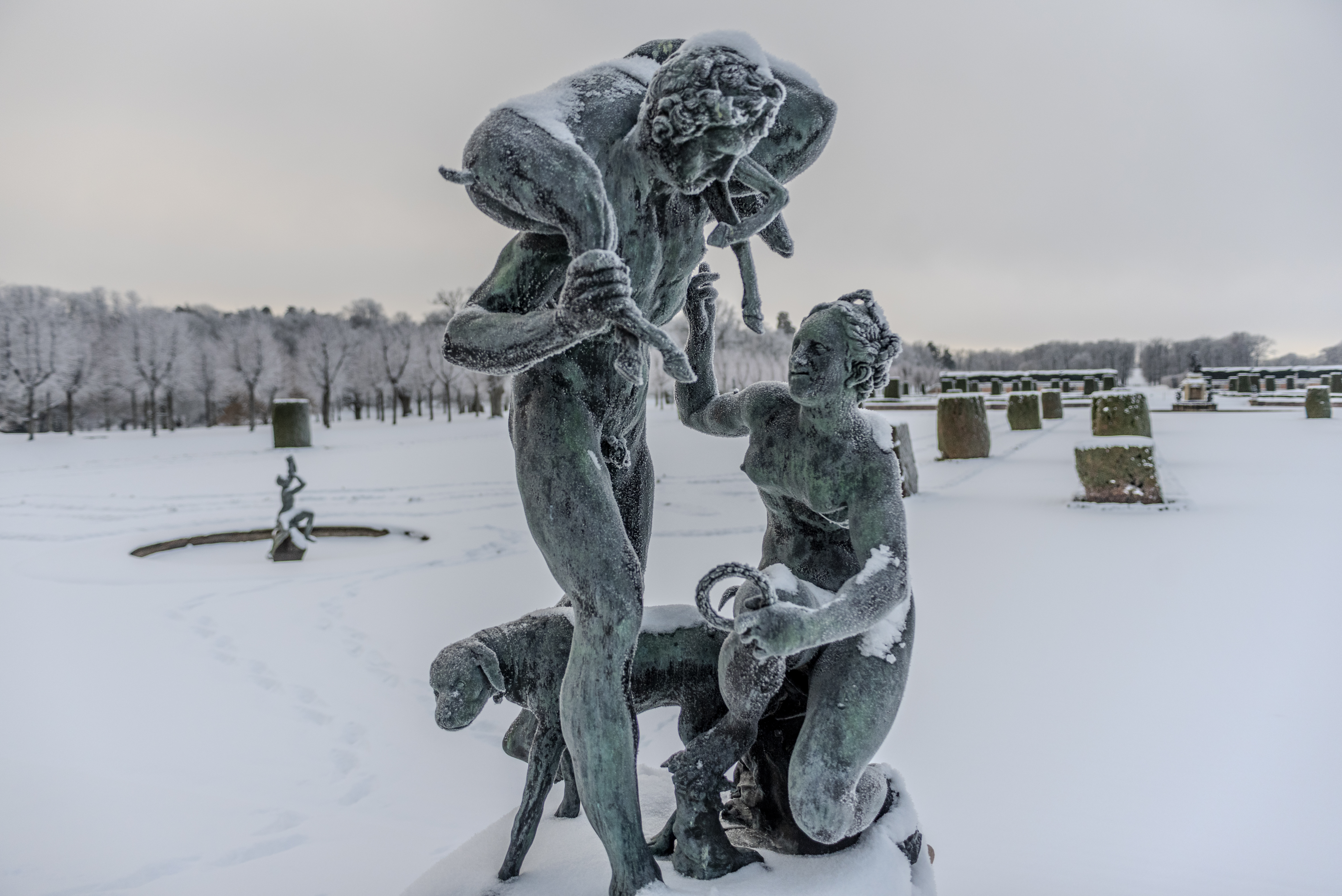 Frostiga brons-statyer framför broderiparterren i Drottningholm. Vinter och snö.