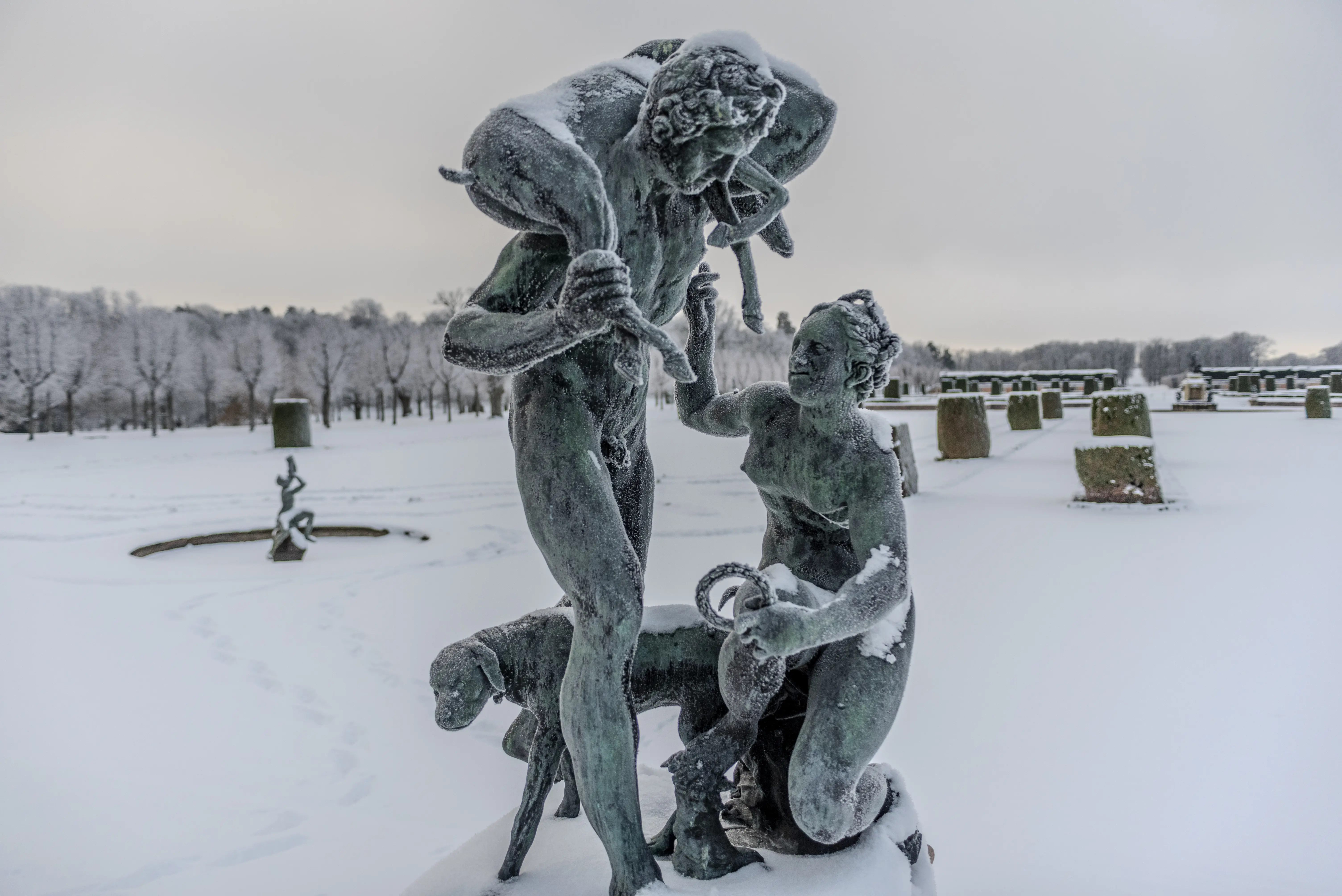 Frostiga brons-statyer framför broderiparterren i Drottningholm. Vinter och snö.
