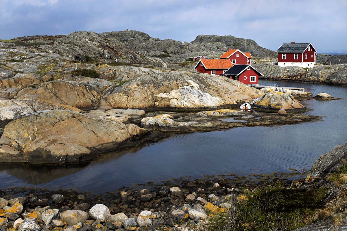 Klippor kring en smal, slingrande vik. Vid vattnet ligger några röda hus.
