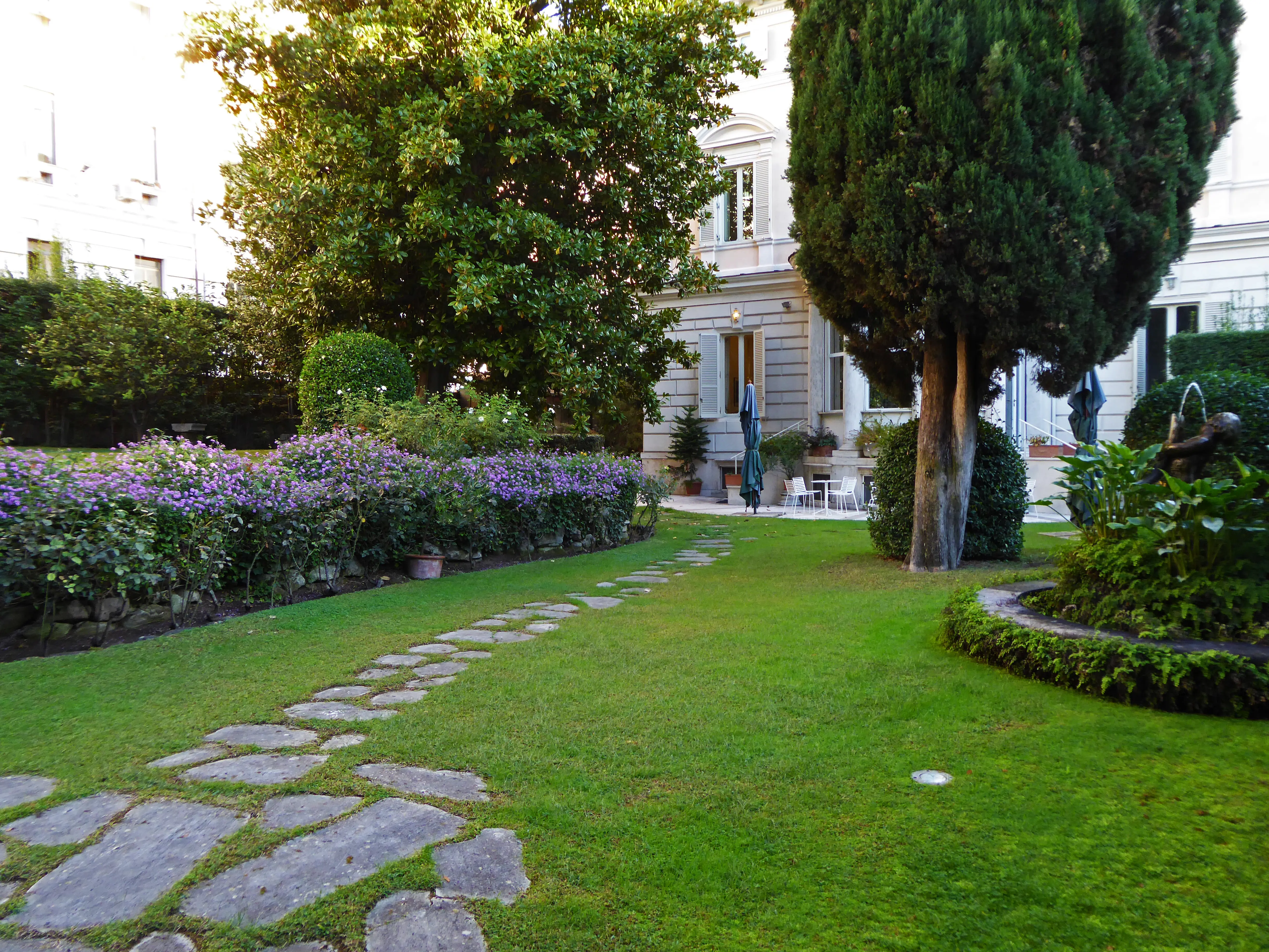 Ambassad-residenset i Rom. Trädgården, med sten-lagd gång, fontän, blommande buskar och stora träd
