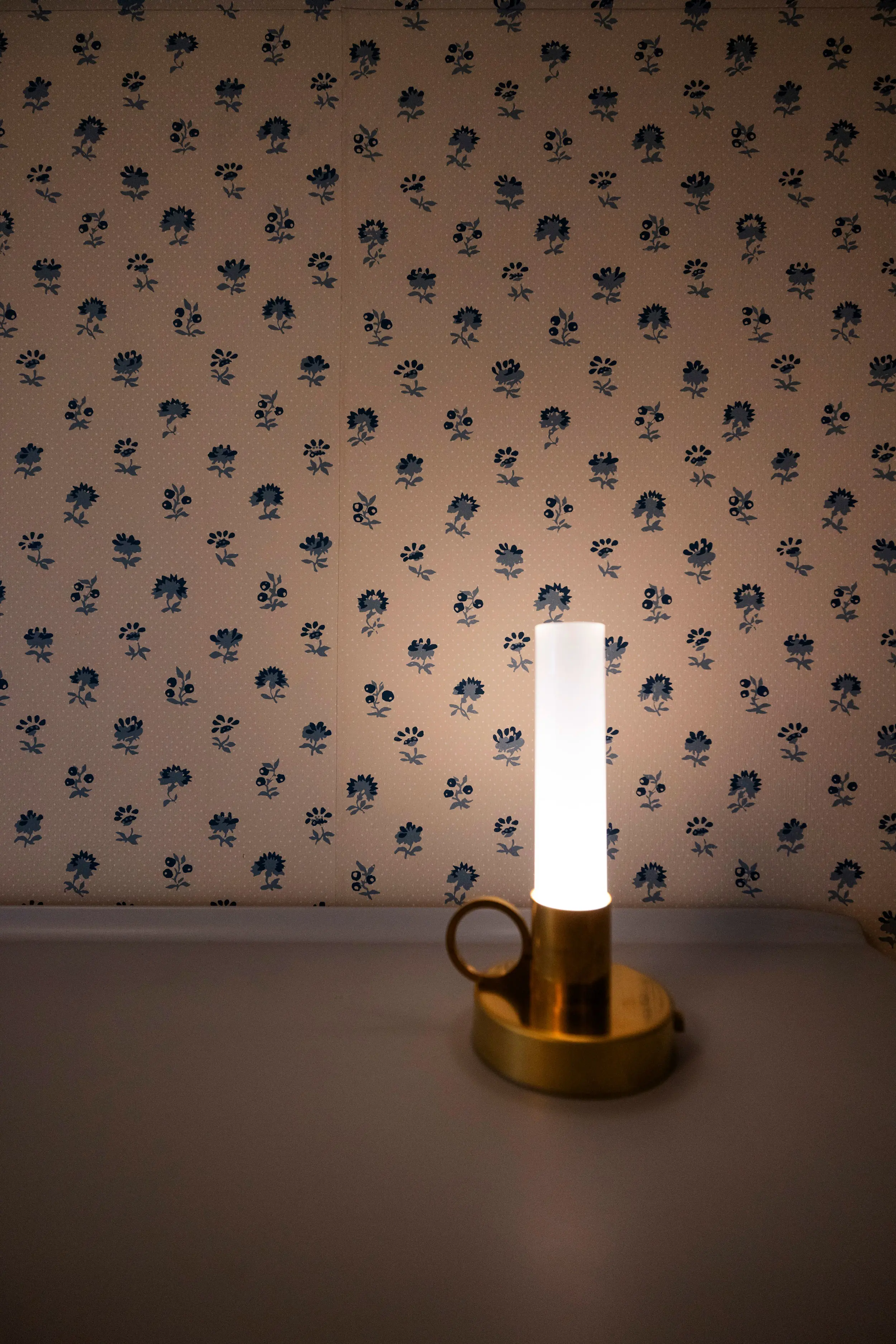 Blåblommig tapet med ljuslykta i förgrunden.