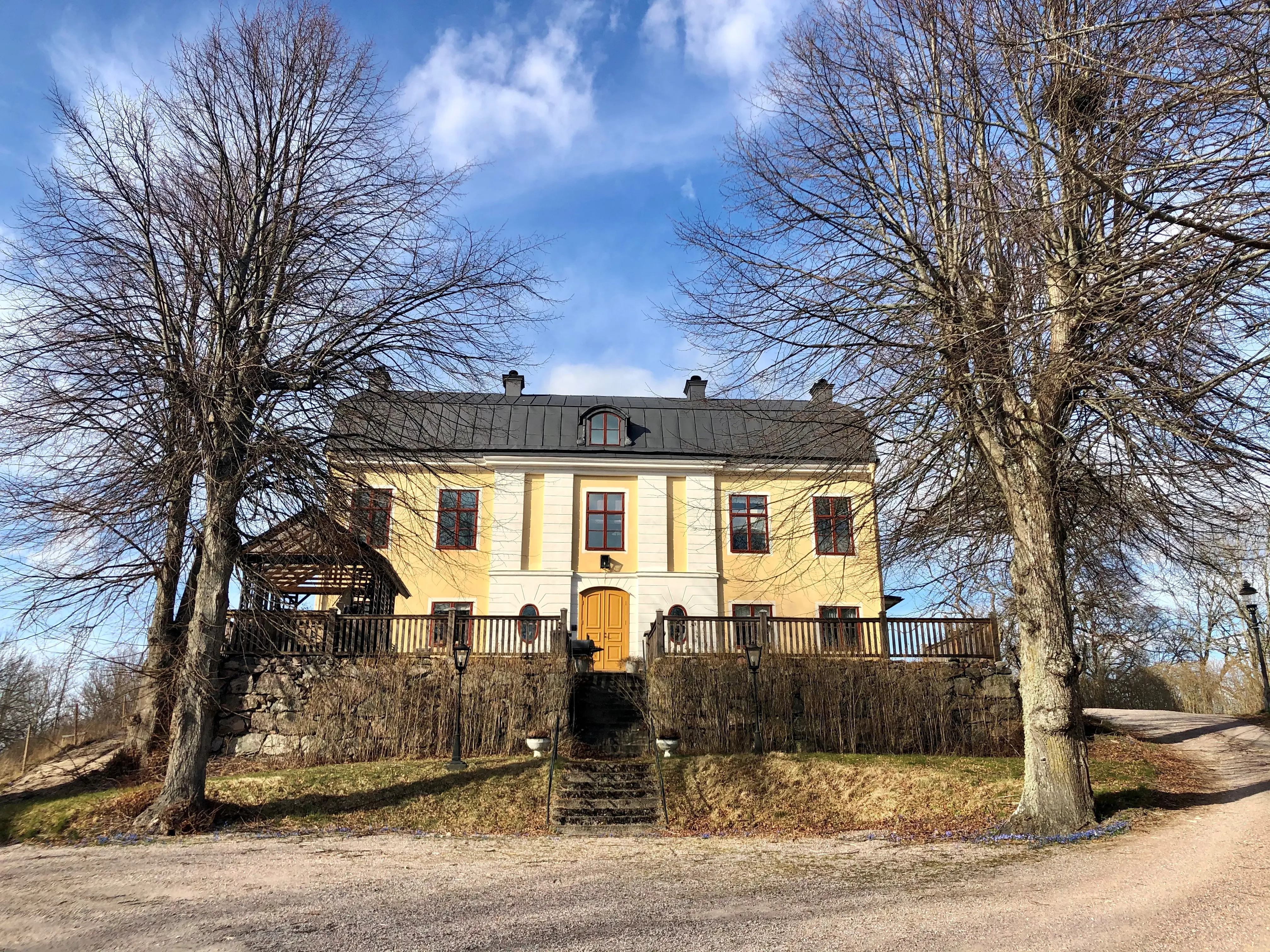 Nuvarande mangårdsbyggnaden på Stora Kungsladugården. Fasaden är gulputsad med vita pilastrar. Tidig vår.