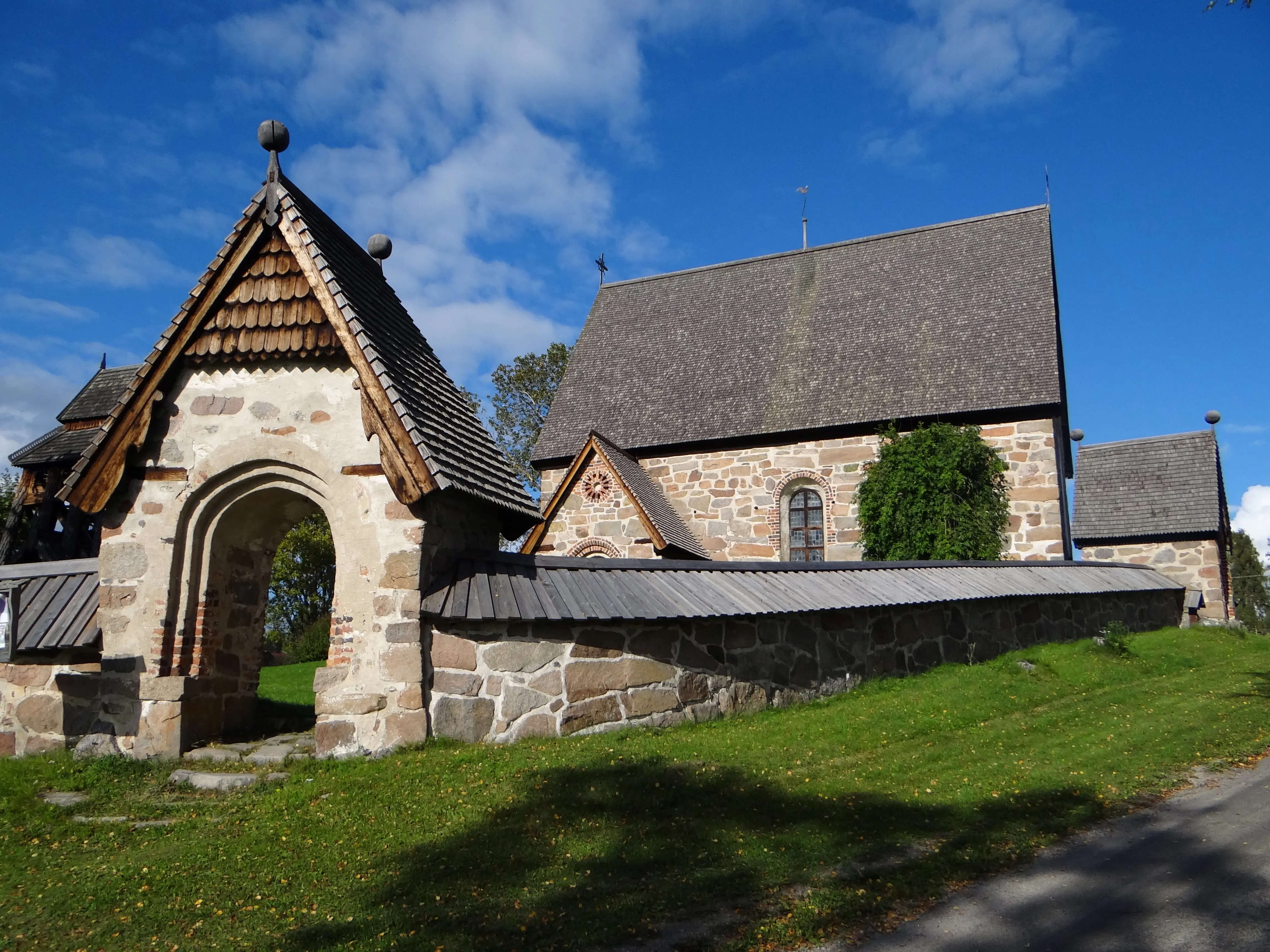 Trönö gamla kyrka. Enkel stenkyrka med spåntak. Runt kyrkogården går en stenmur med portaler som också har spåntak.