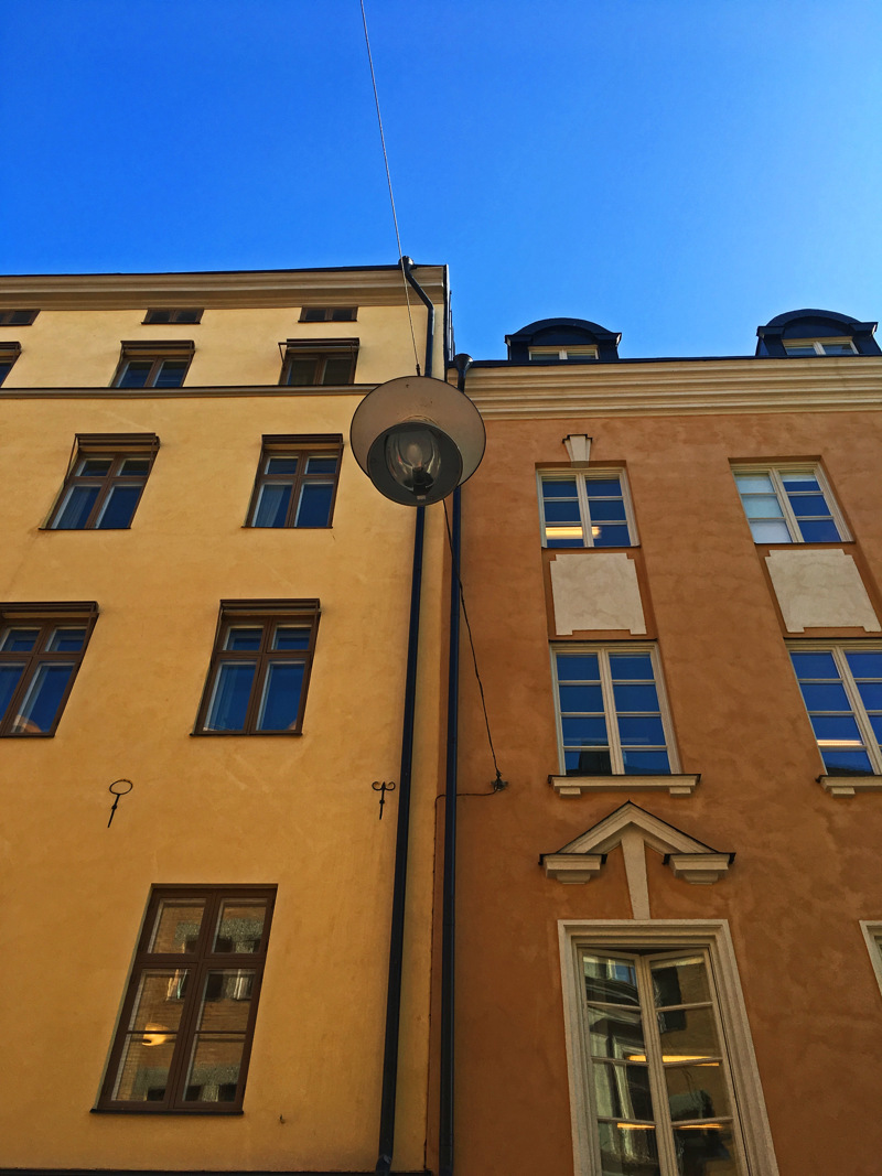 En byggnad med gulputsad fasad och ankarslut bredvid en något lägre byggnad med brun puts.