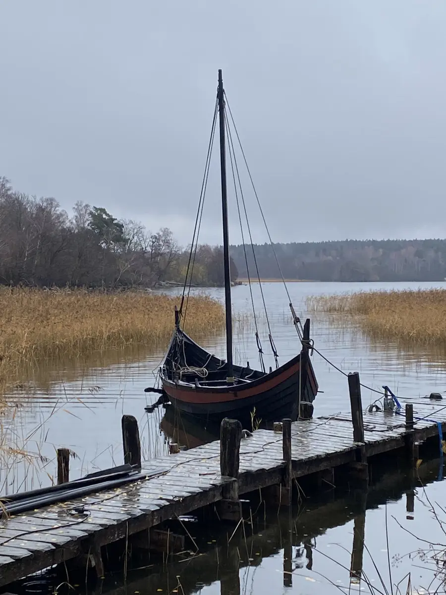Rekonstruerad båt från vikingatiden förtöjd vid en brygga.
