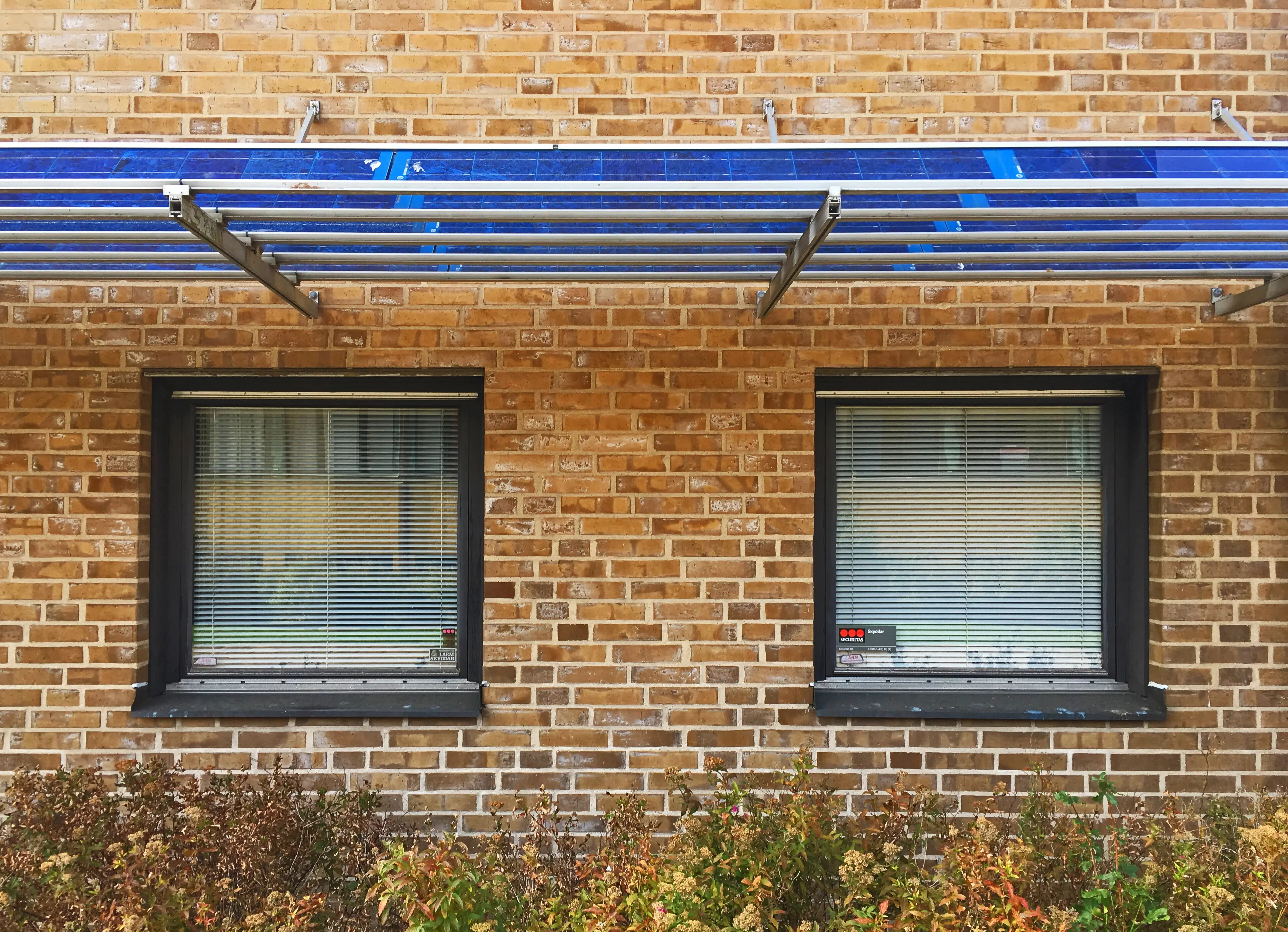 Detalj av Musikhögskolans fasad. Fönster som skuggas av blå solpaneler.