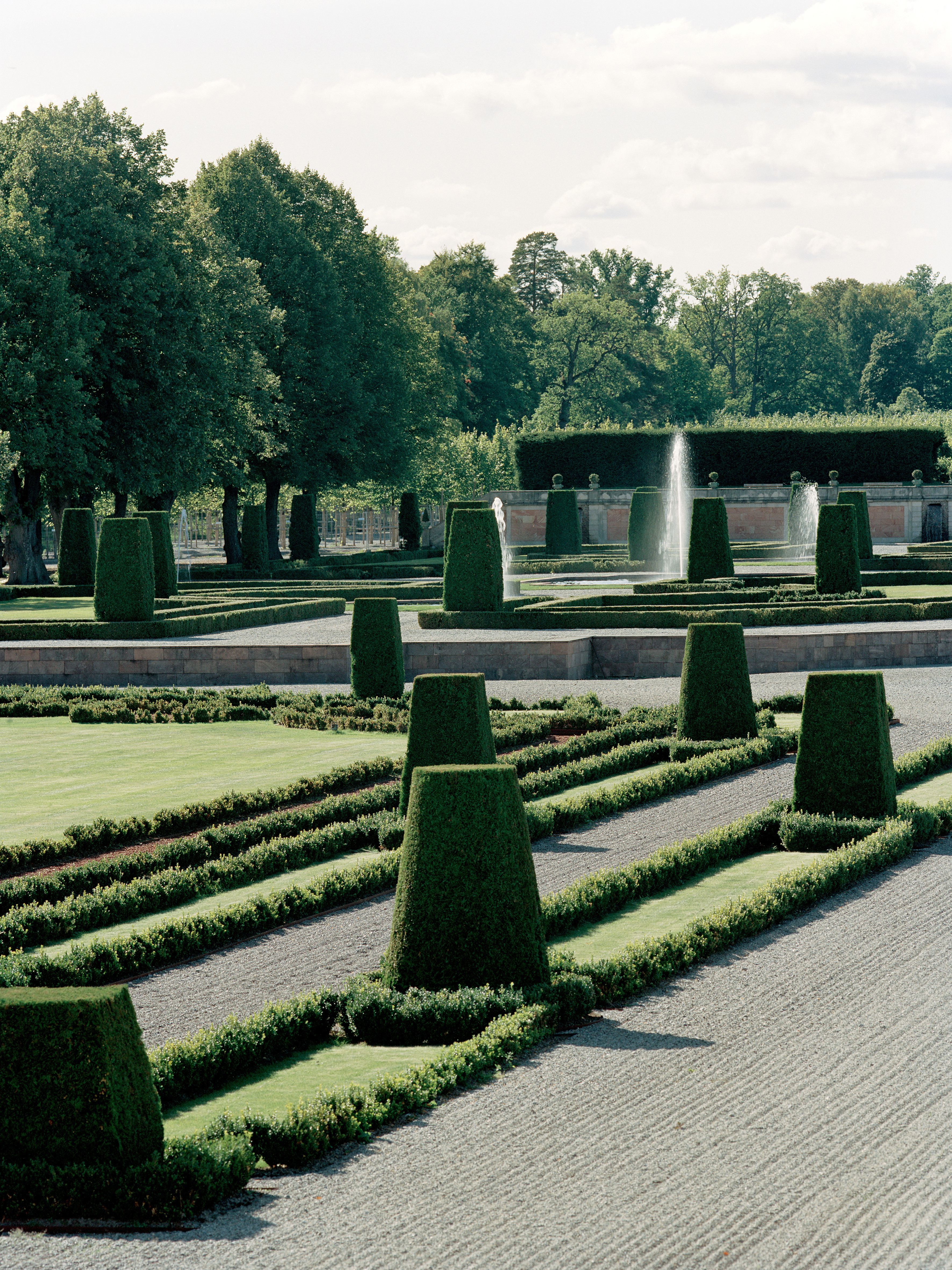 Del av barock-trädgården vid Drottningholm, med fontäner och form-klippt buxbom. Sommar och grönska.