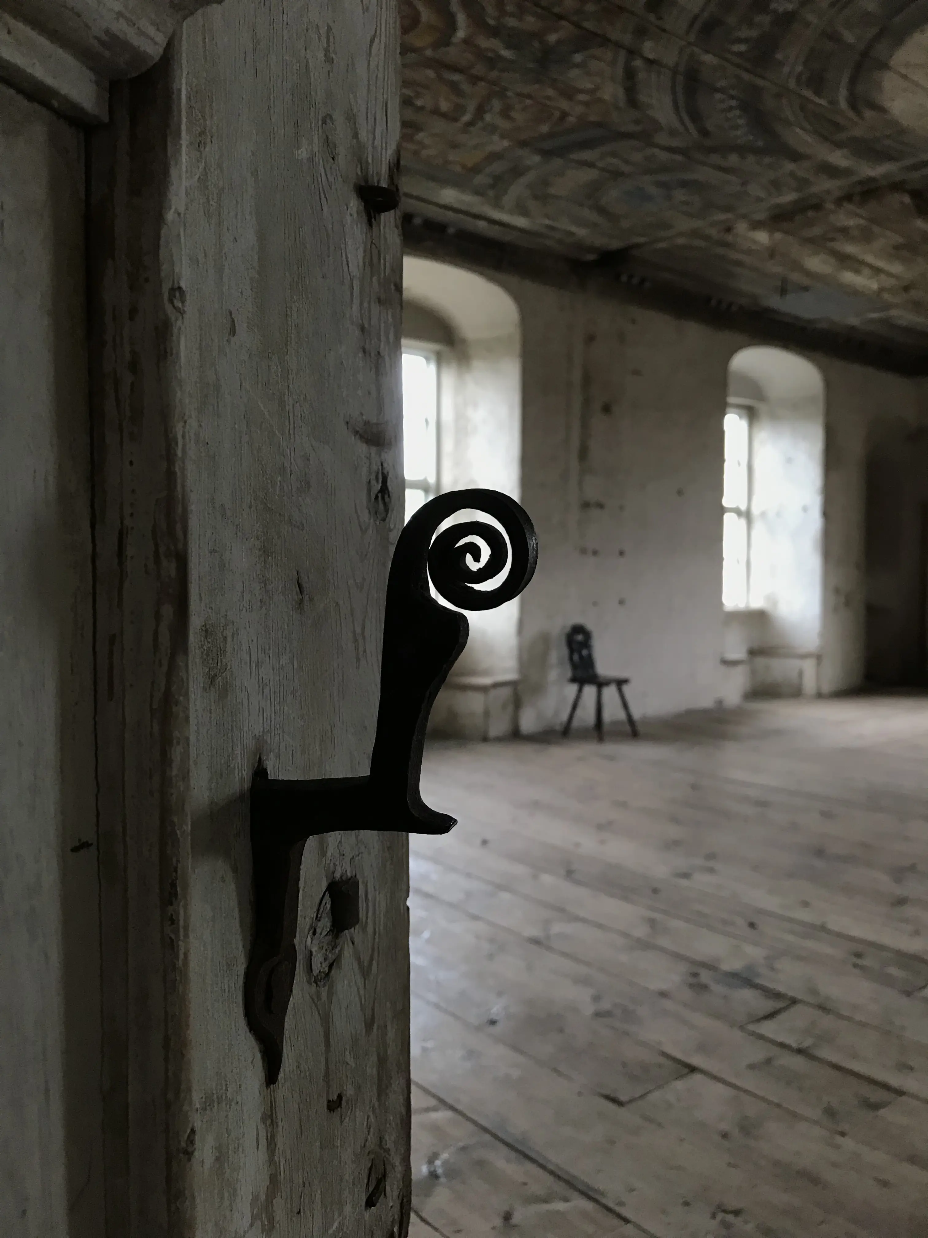 Interiör, Bogesunds slott. Dörr till en sal med trägolv och målat trätak. Dörrhandtaget är i svart smide. Änden är rullad till en spiral.