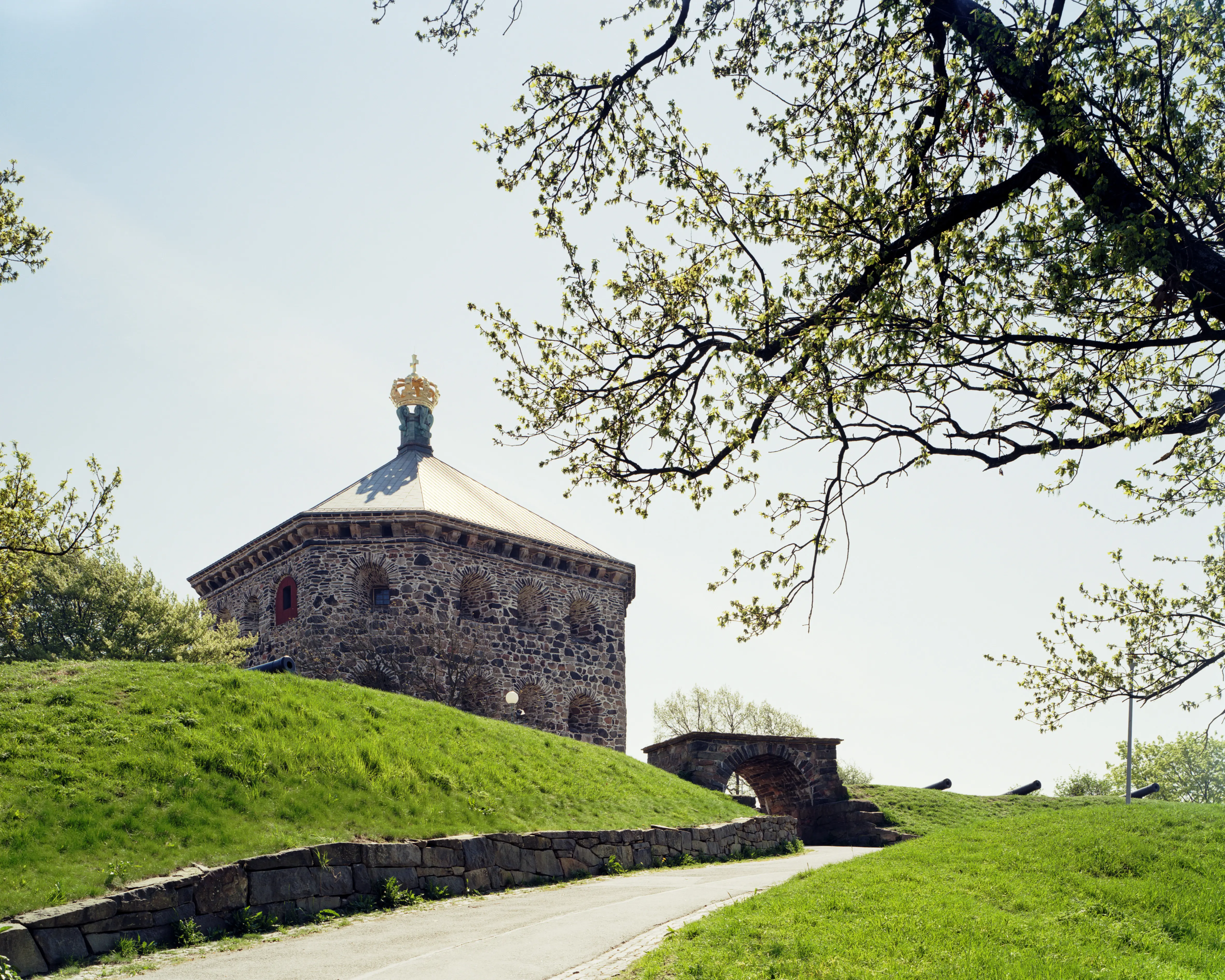 Skansen Kronan. Åttakantigt stentorn omgivet av en gräsvall med kanoner och en stenportal. Vår och grönska.