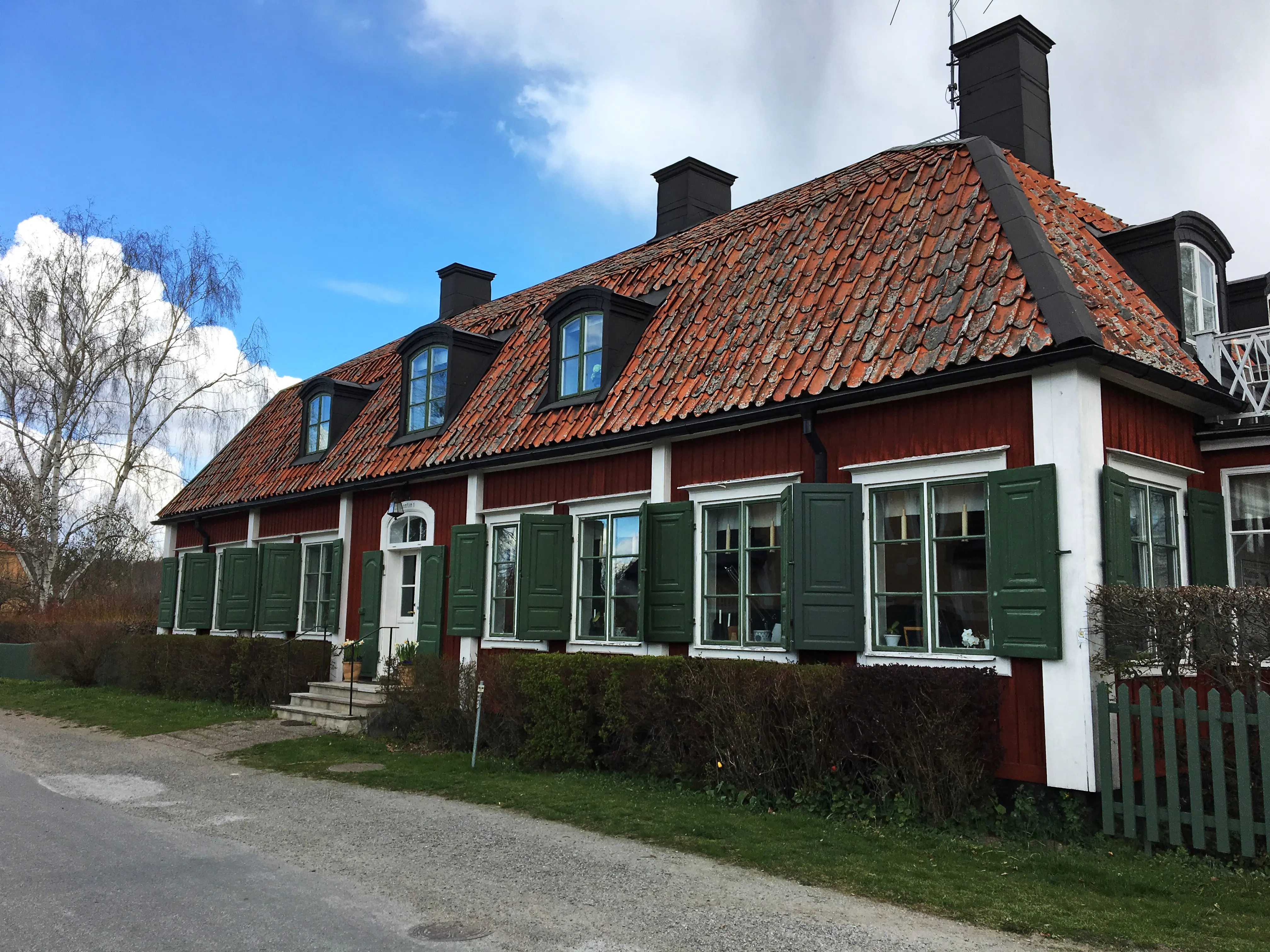 Kanton 1. Rött hus med gröna fönsterluckor. Tegeltaket har tak-kupor.