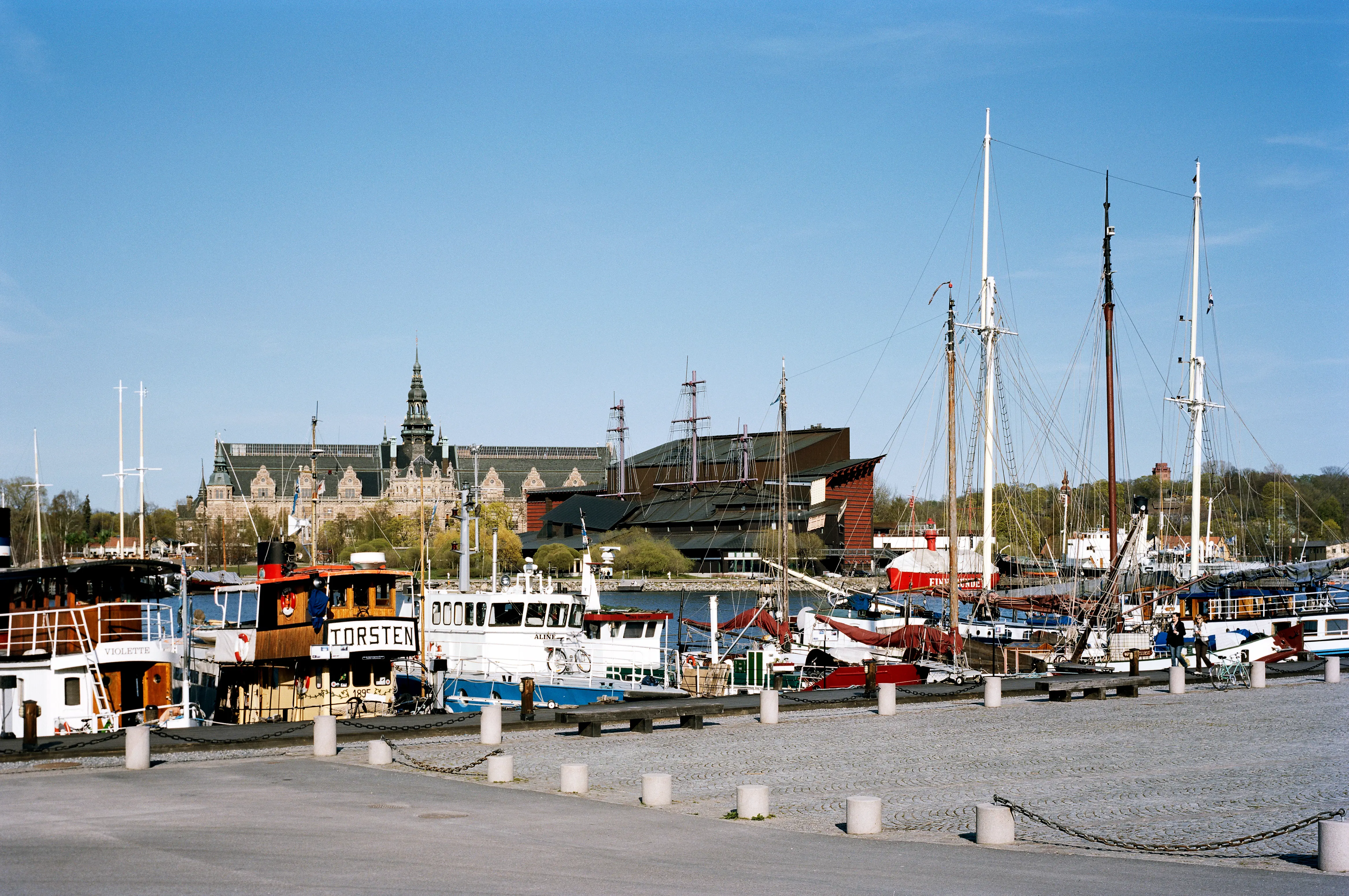 Vasamuseet sett över Nybroviken. Mellan båtmasterna vid kajen syns museets stiliserade master på taket.