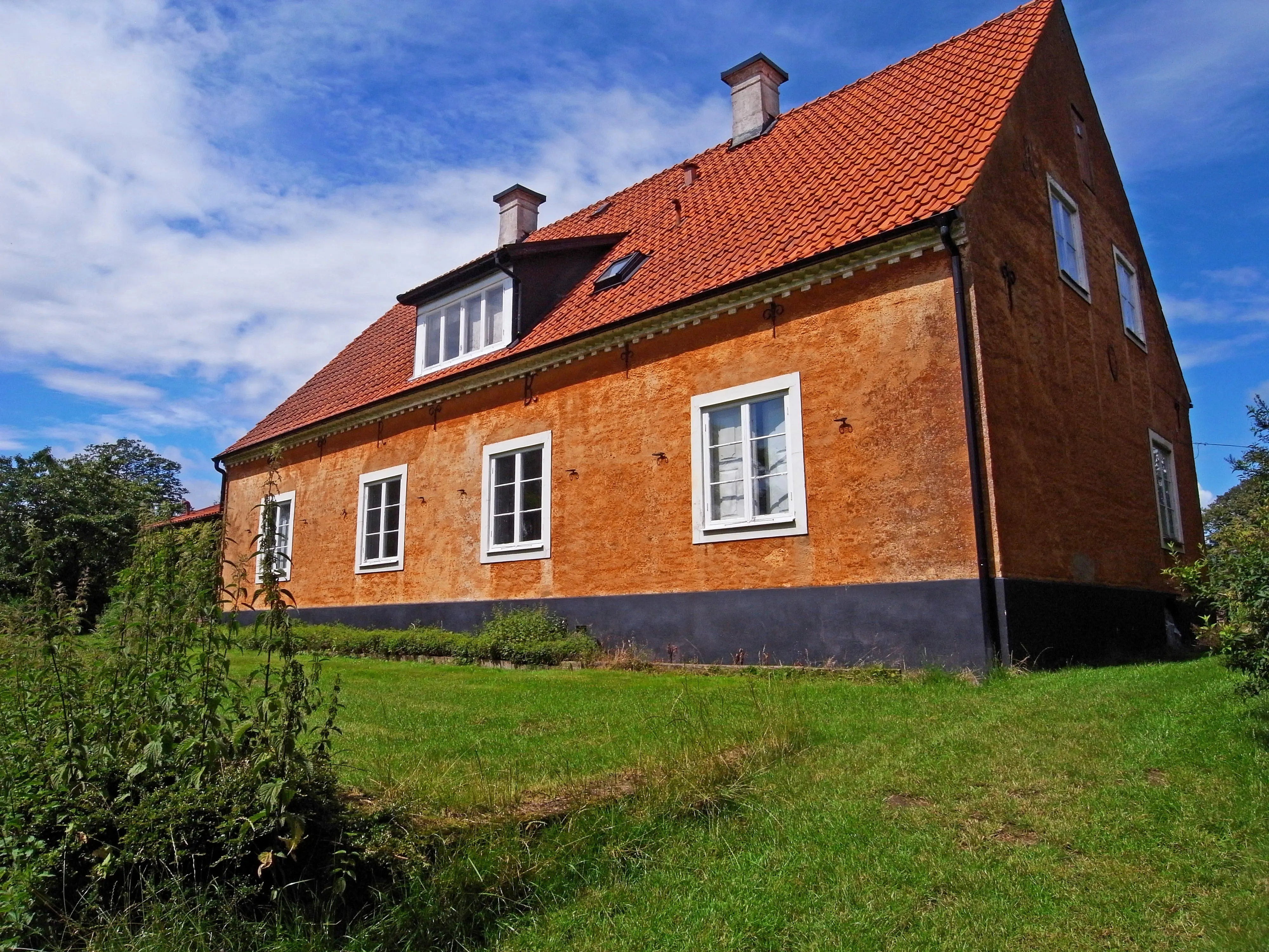 Mangårdsbyggnaden på Hjälmshult. Stenbyggnad klädd i orange puts. Fasaden pryds av ankarslut och diskret stuckatur.