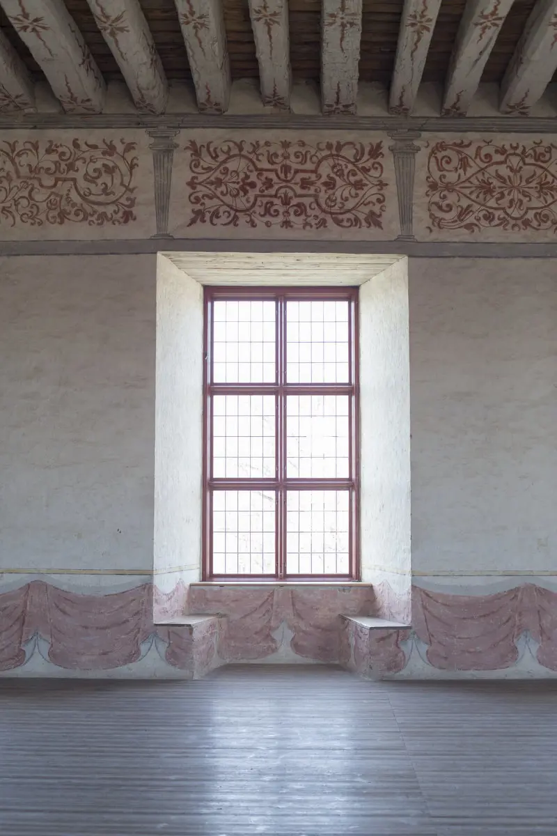 Interiör, Vadstena slott. Sal med stora fönster i djupa nischer med bänkar. Tak och väggar har röda dekormålningar.