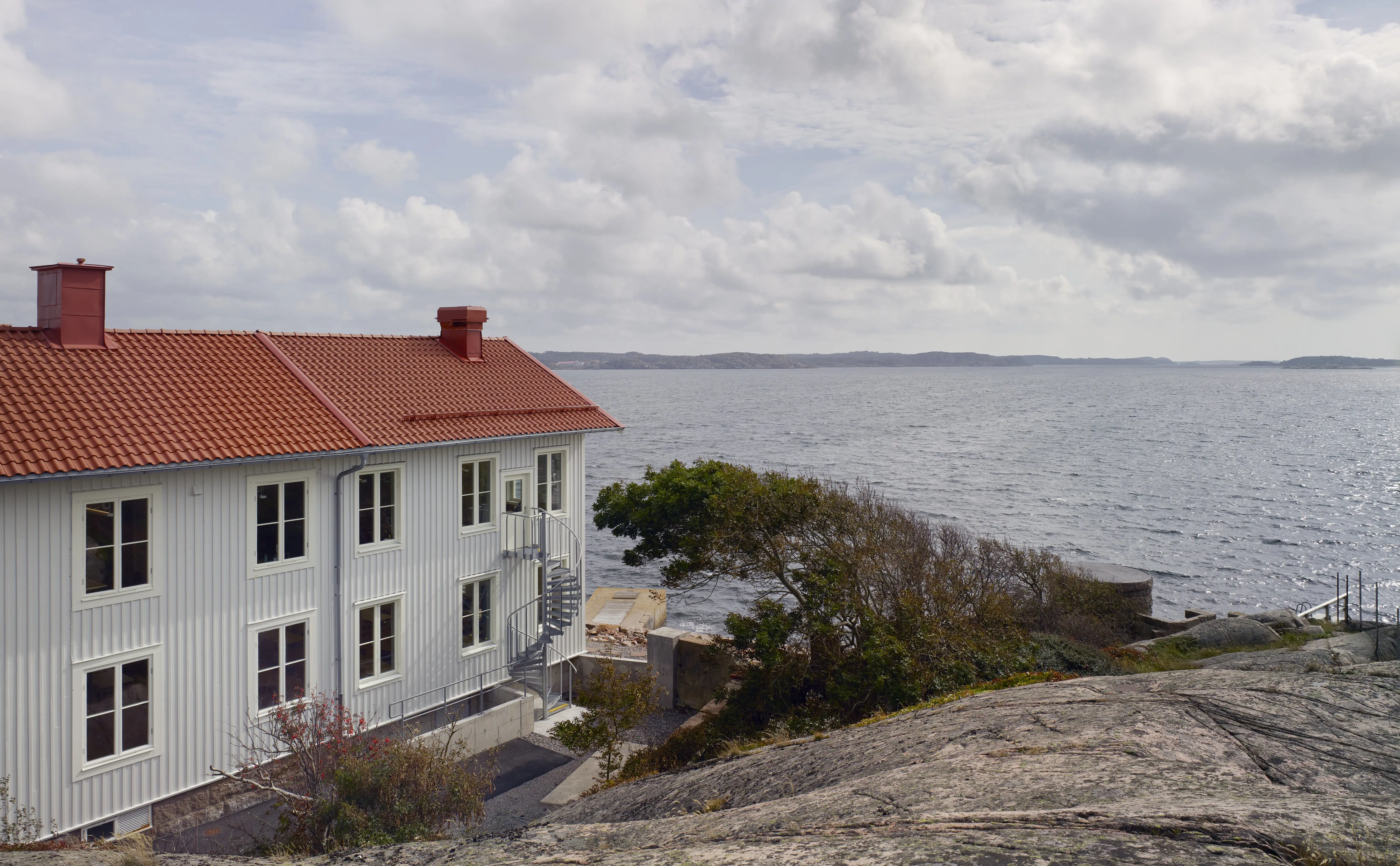 Havsfiskelaboratoriet i Lysekil, en vit tvåvåningsbyggnad bland klipporna. Vy ut mot havet.