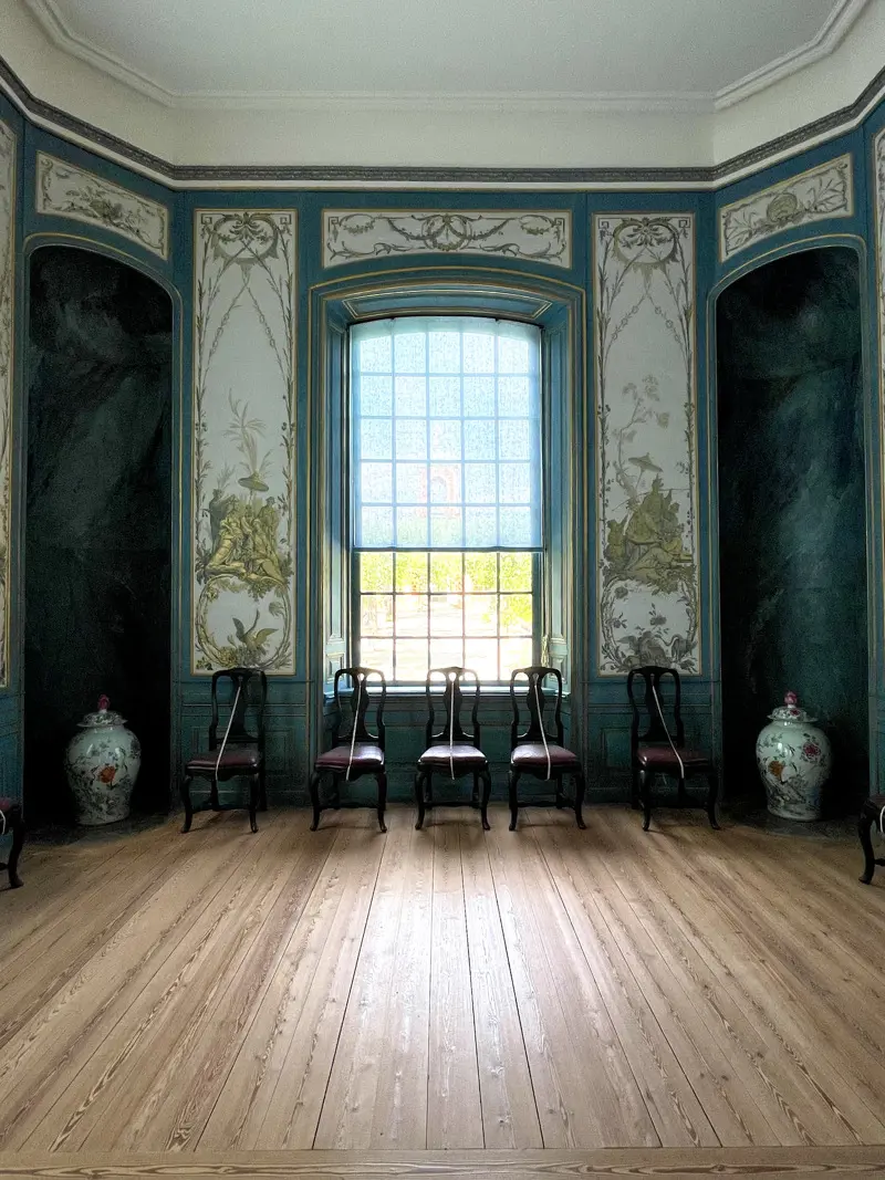 Interiör från Kina slott. En sal med trägolv, tapeter med växtmotiv och ett stort spröjsat fönster.
