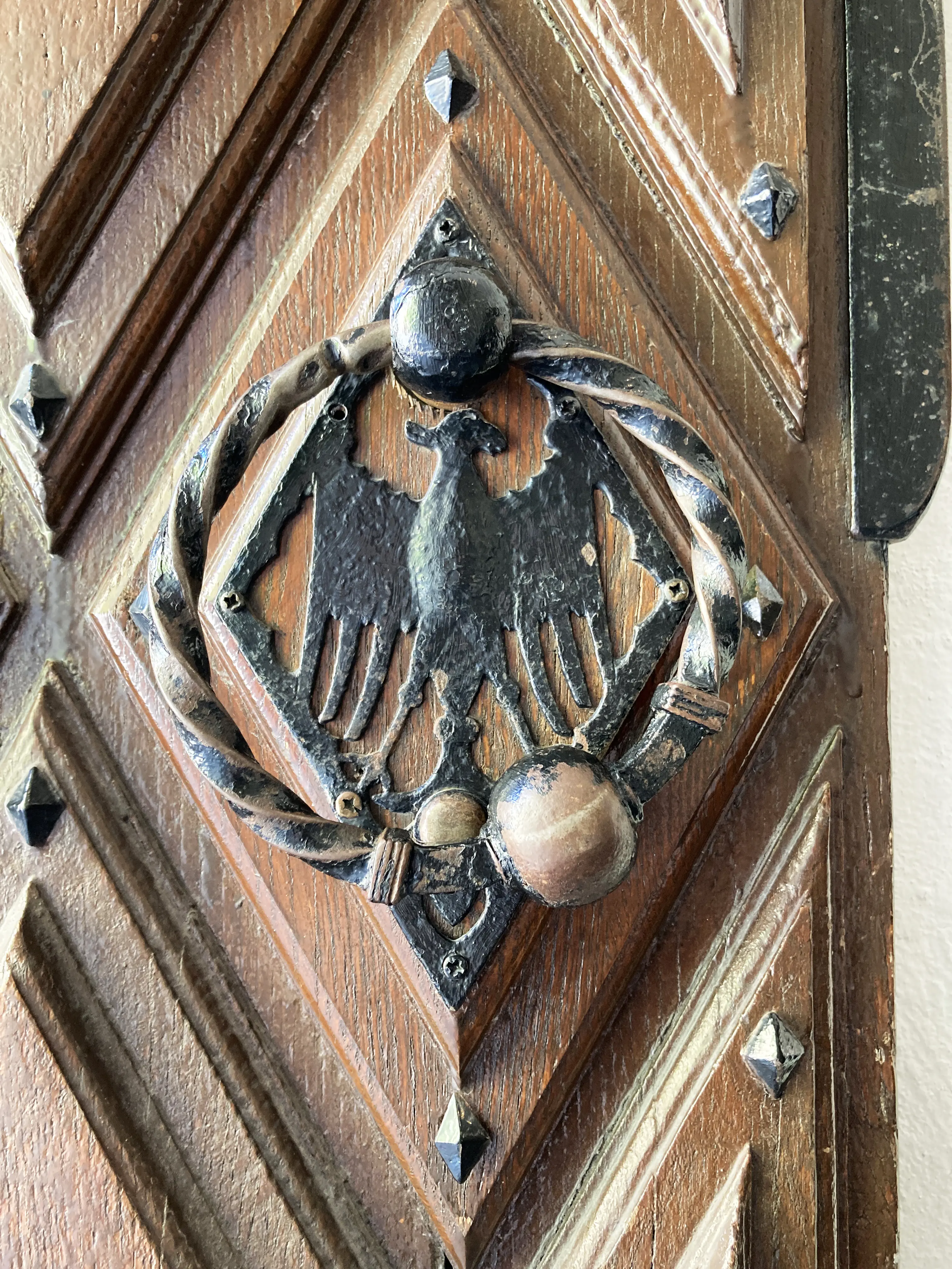 Örebro slott. Detalj från en trädörr med smidesdetaljer. Ett svartmålat mässingsbeslag har formen av ett bevingat djur.