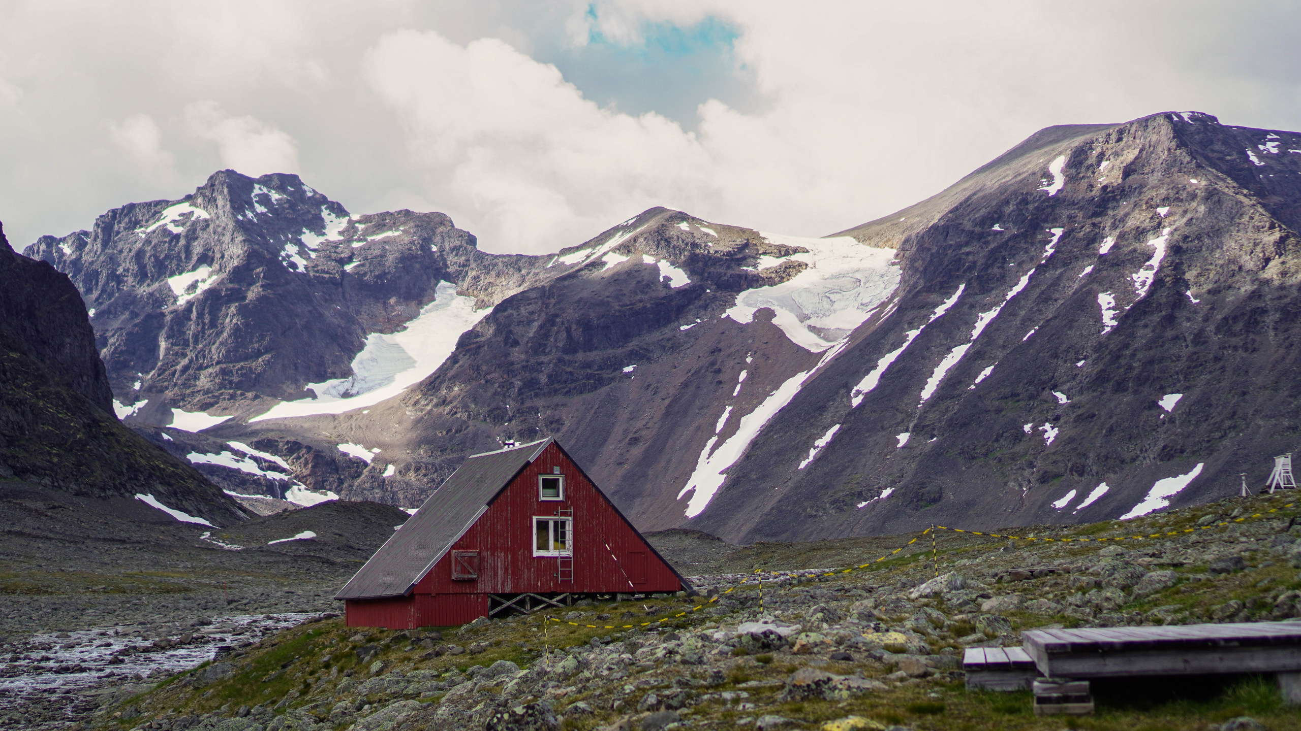 Rött hus med höga fjäll i bakgrunden.