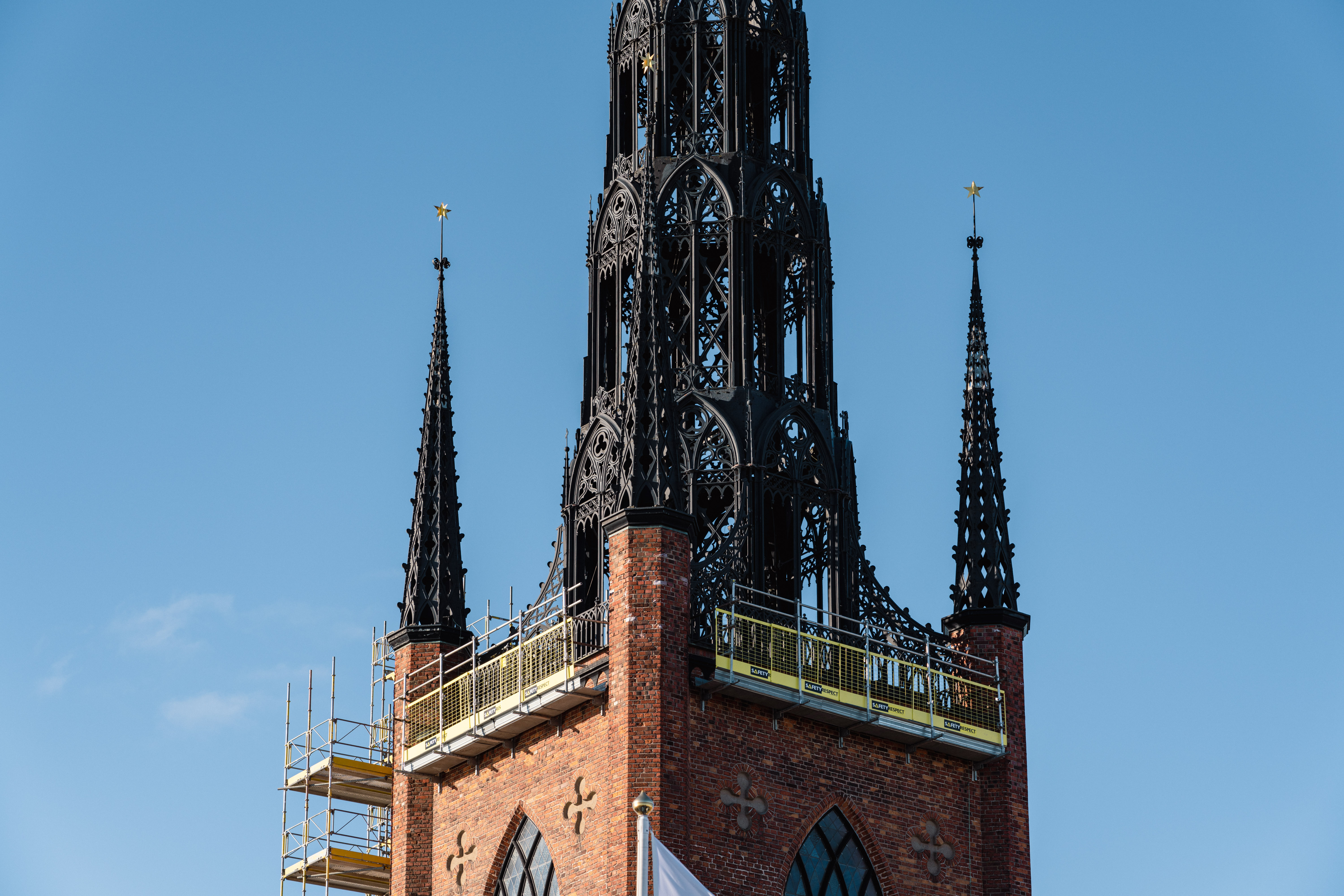 Torn i tegel med tre spiror mot blå himmel