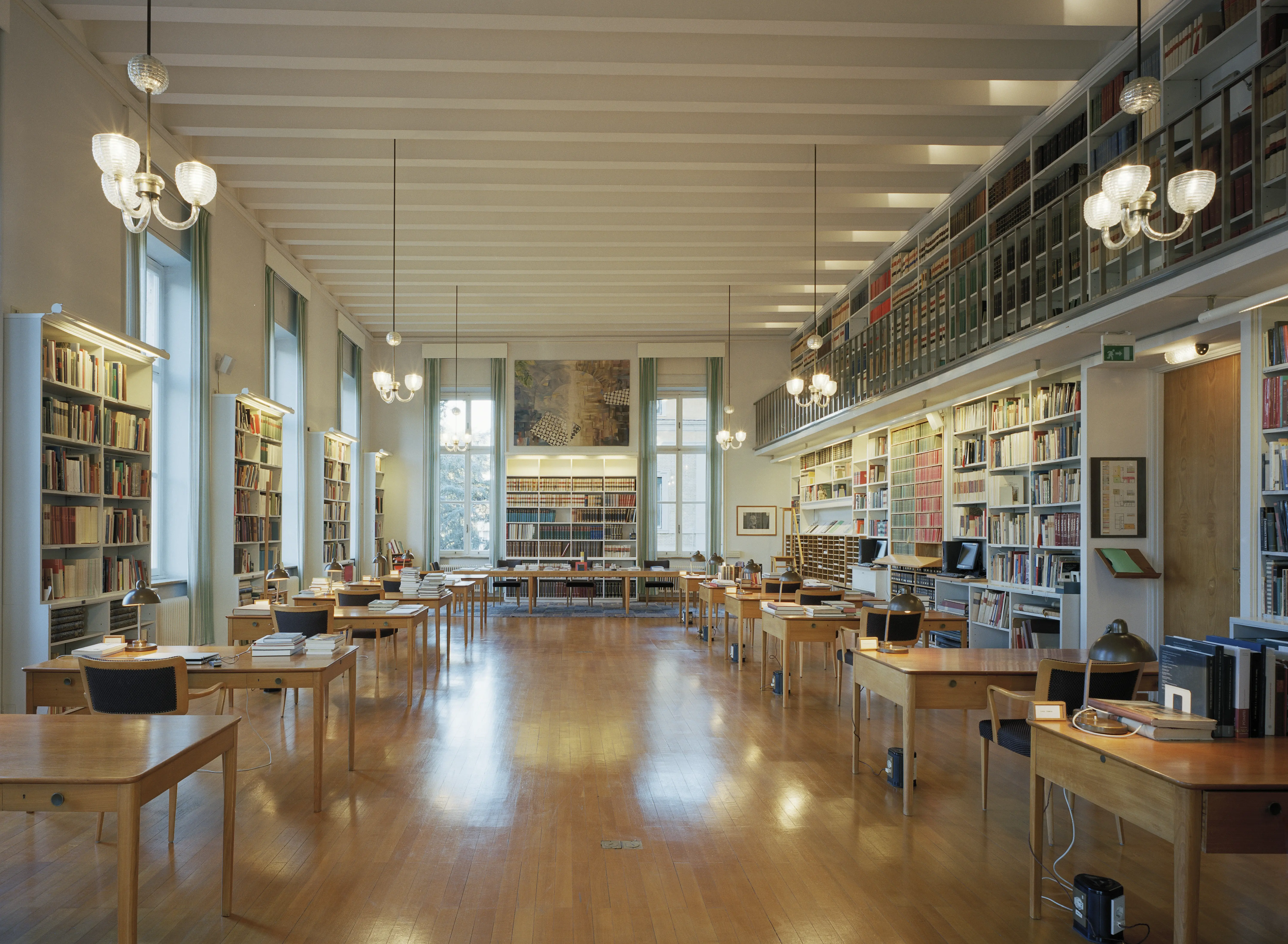 Interiör, svenska institutet i Rom. Bibliotek och läsesal. Ljuset från de höga fönstren speglas i trägolvet.