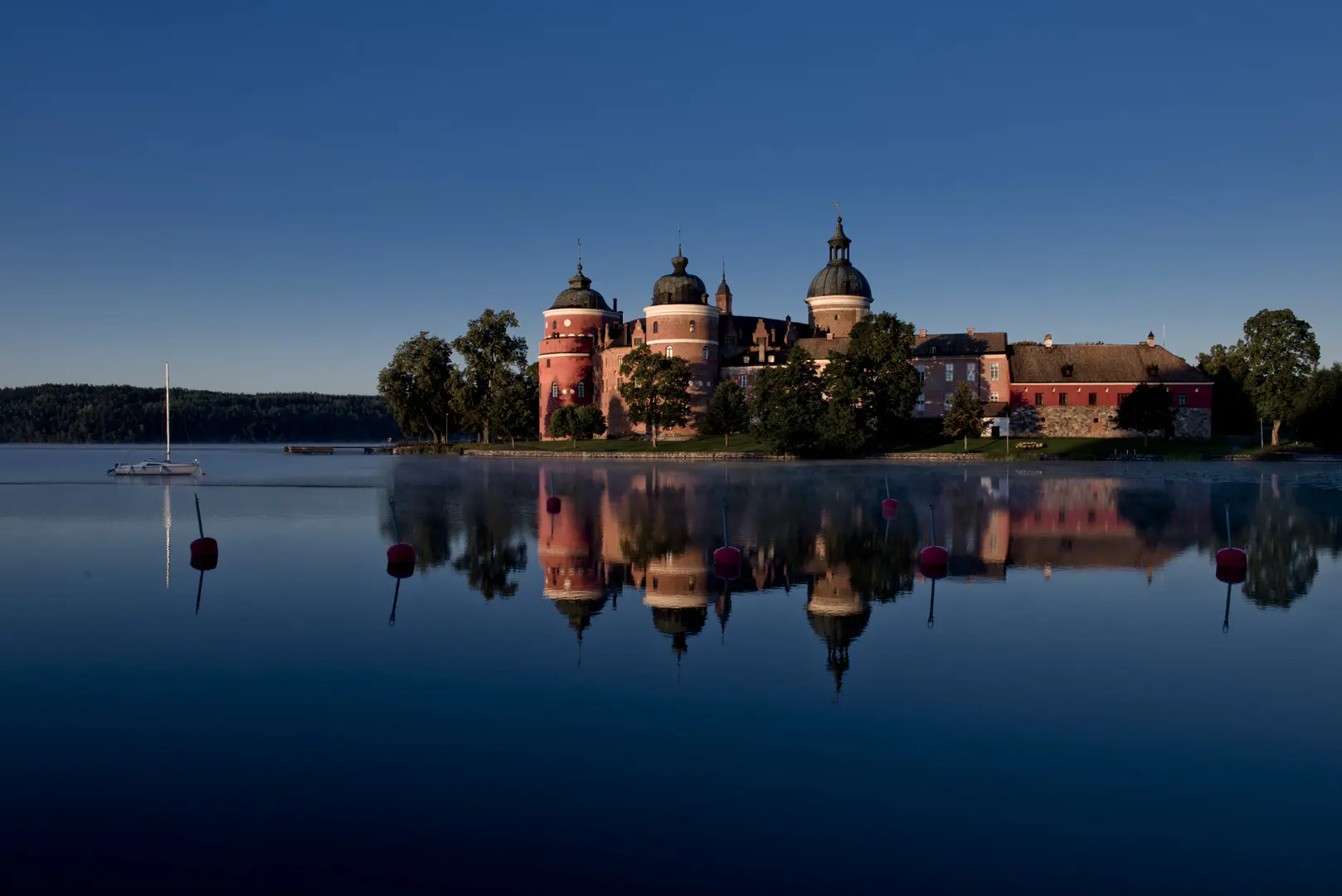 Gripsholms slott på natten. Slottet speglas i det omgivande vattnet.