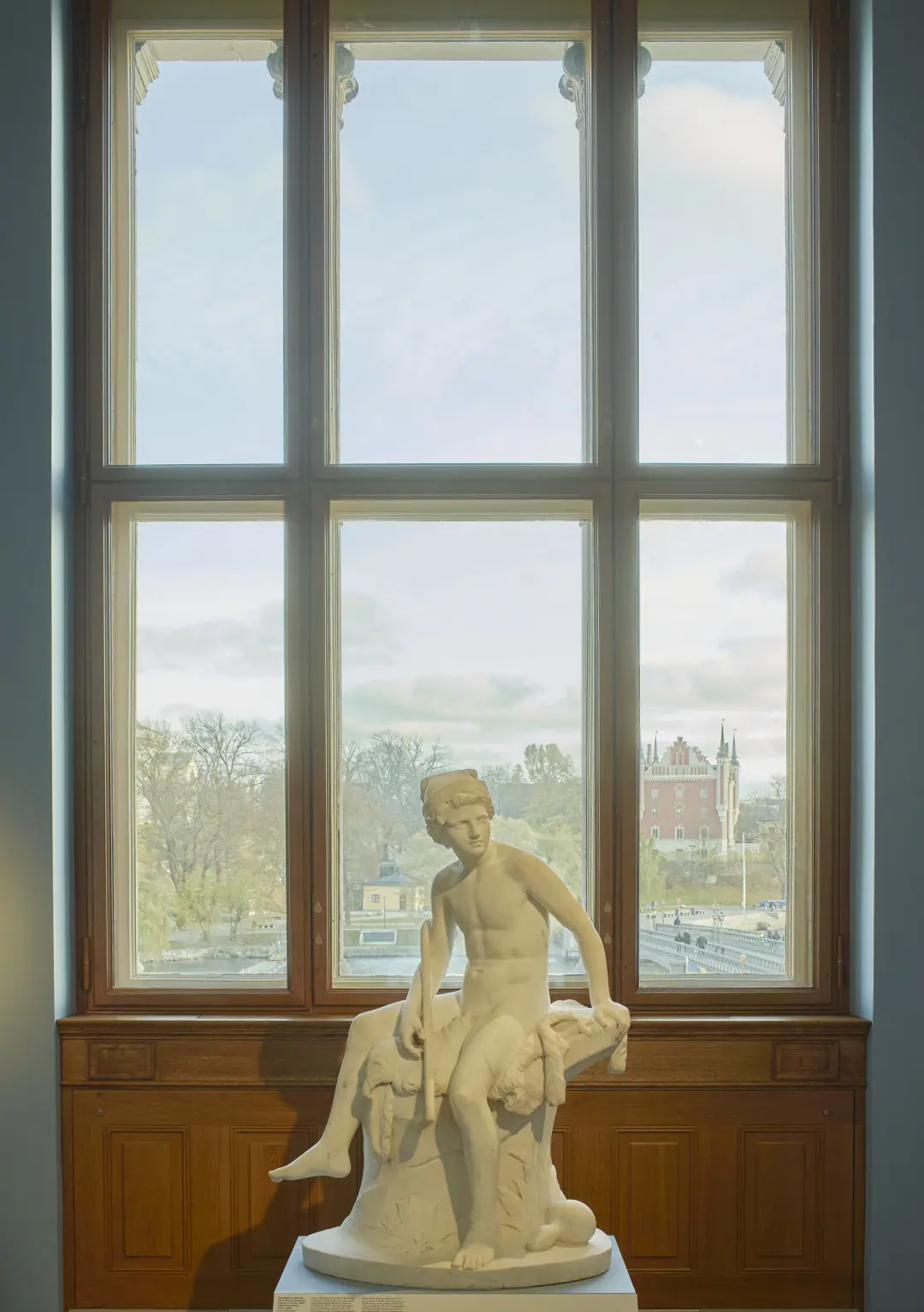 Skulptur framför ett fönster med utsikt mot Skeppsholmen och Amiralitetshuset.