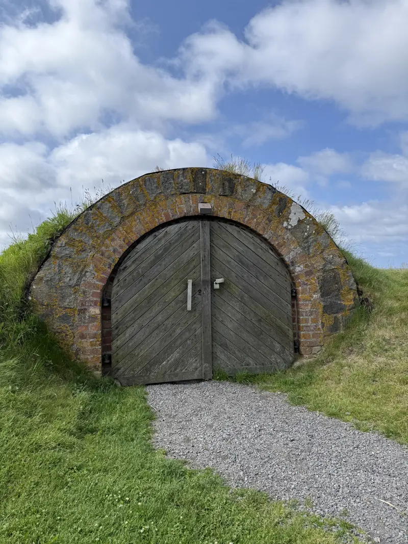 Oval trädörr omringad av tegel och grönt gräs