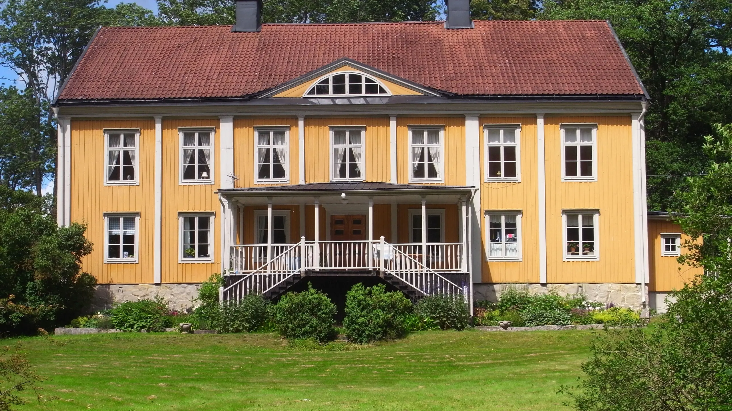 Gul byggnad med tegeltak och många fönster