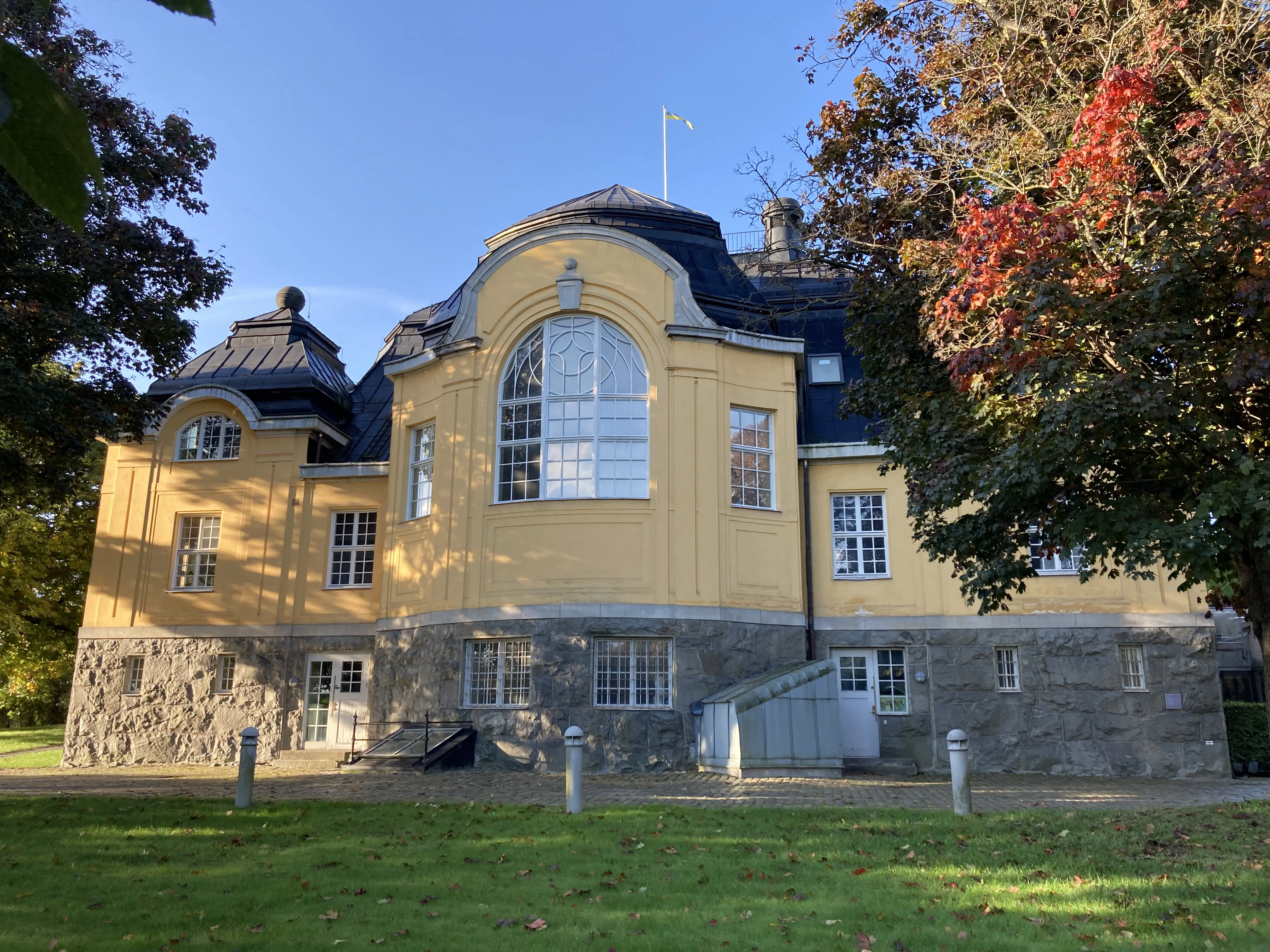 Haga tingshus sett från trädgården. En gulputsad villa med sockelvåning i sten. Fasaden och taket har rundade former.