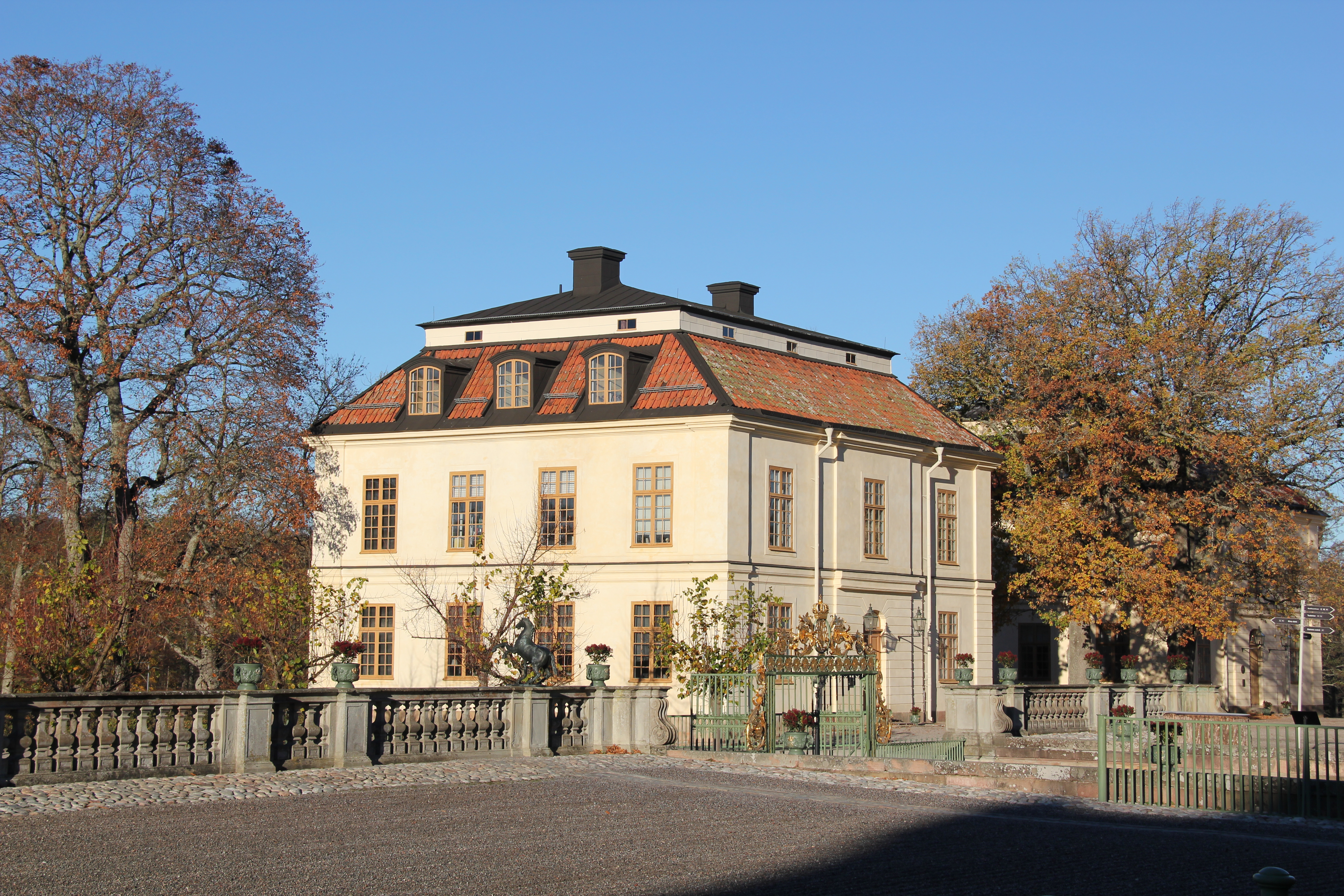 Drottningens paviljong vid Drottningholms slott. En nästan kub-formad byggnad i två våningar, med brutet tak och tak-kupor. Höst