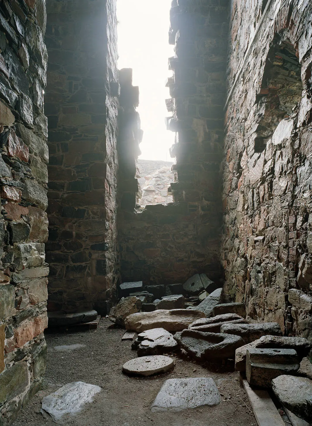 Inne i Bohus fästning. En av stenväggarna är delvis raserad och släpper in ljus.