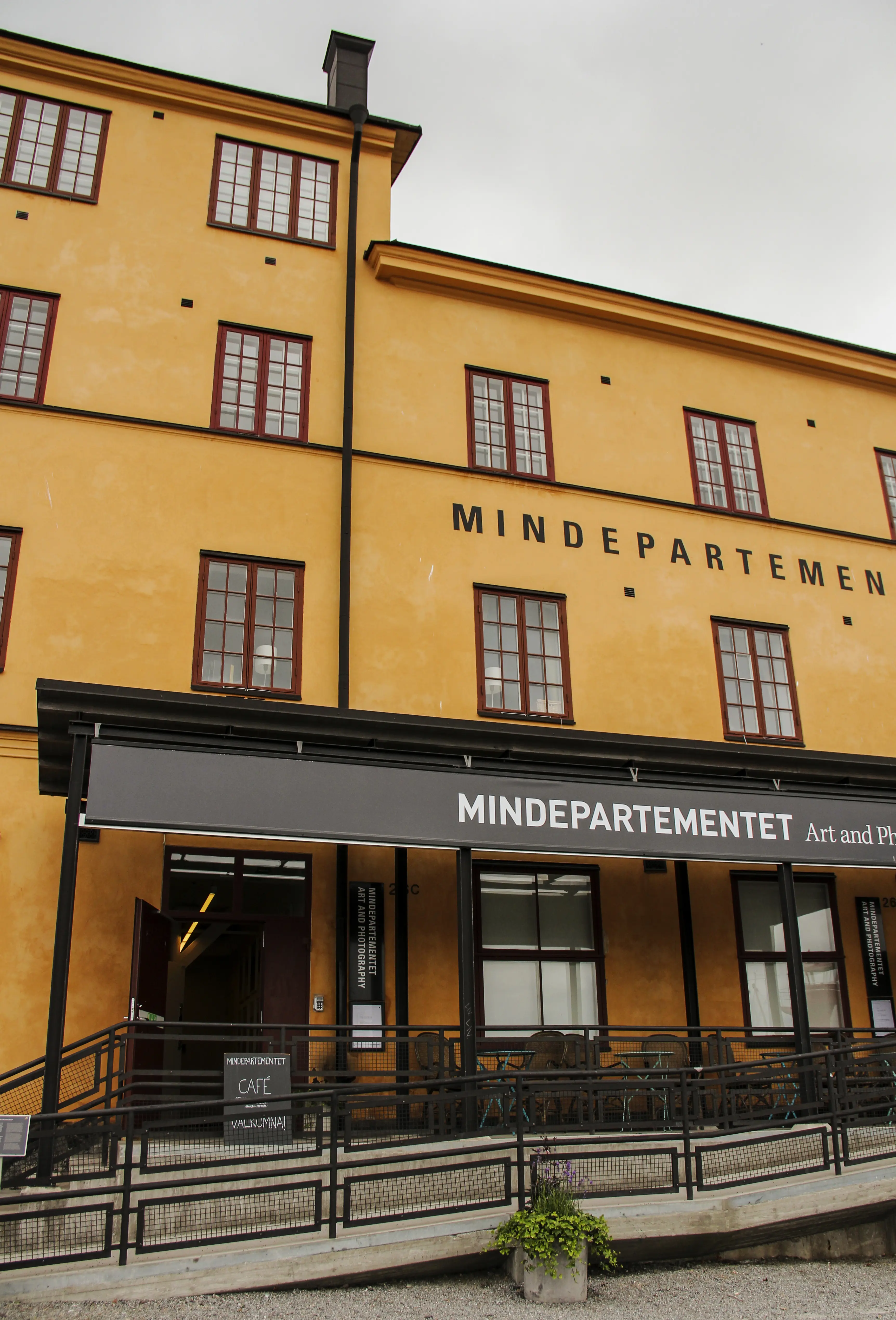 Entré till mindepartementet på Skeppholmen. En snygg rullstolsramp i betong leder upp till uteservering och ingång.