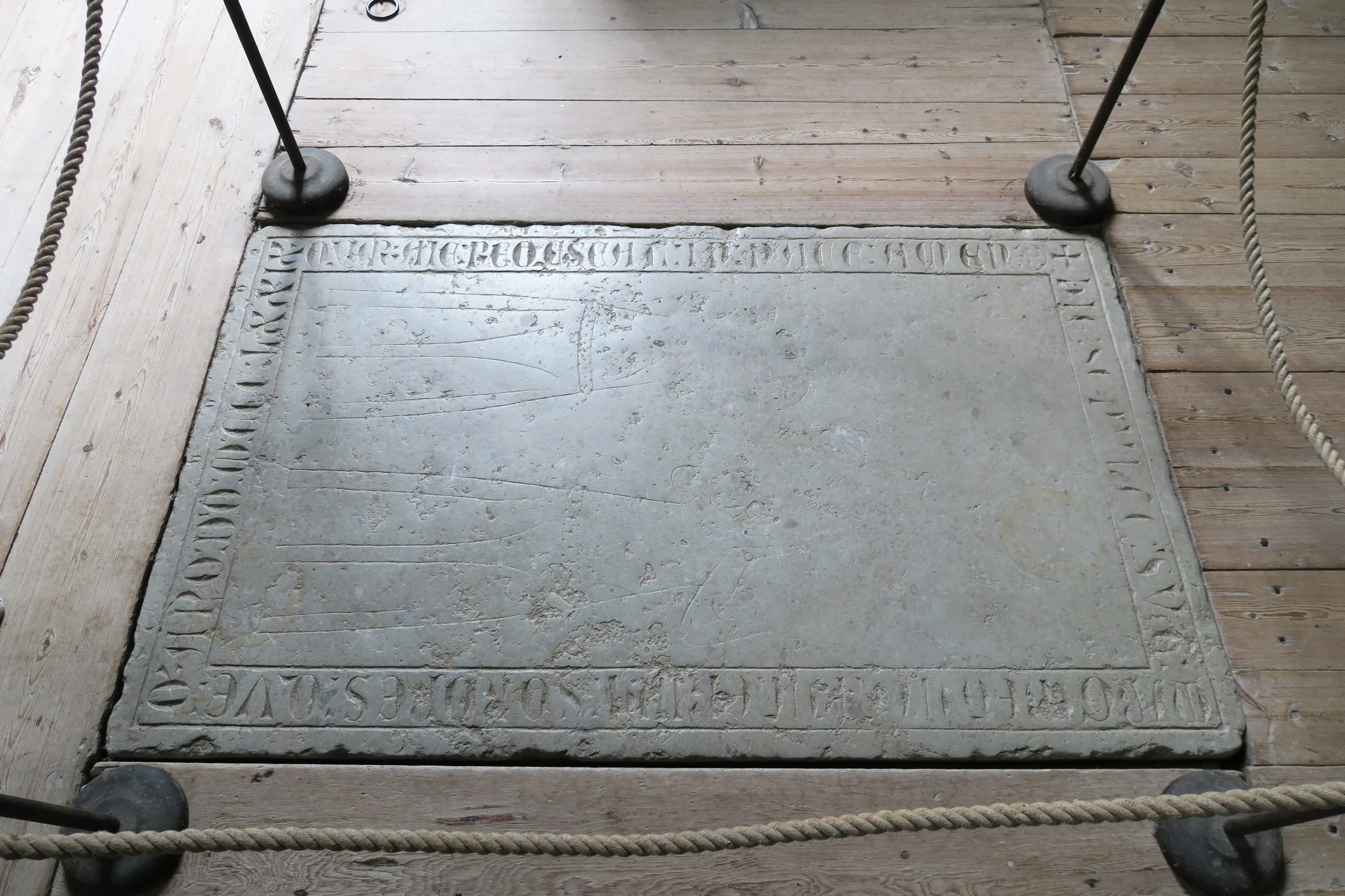 Enångers gamla kyrka. Stenhäll med nött inskription i trägolvet.