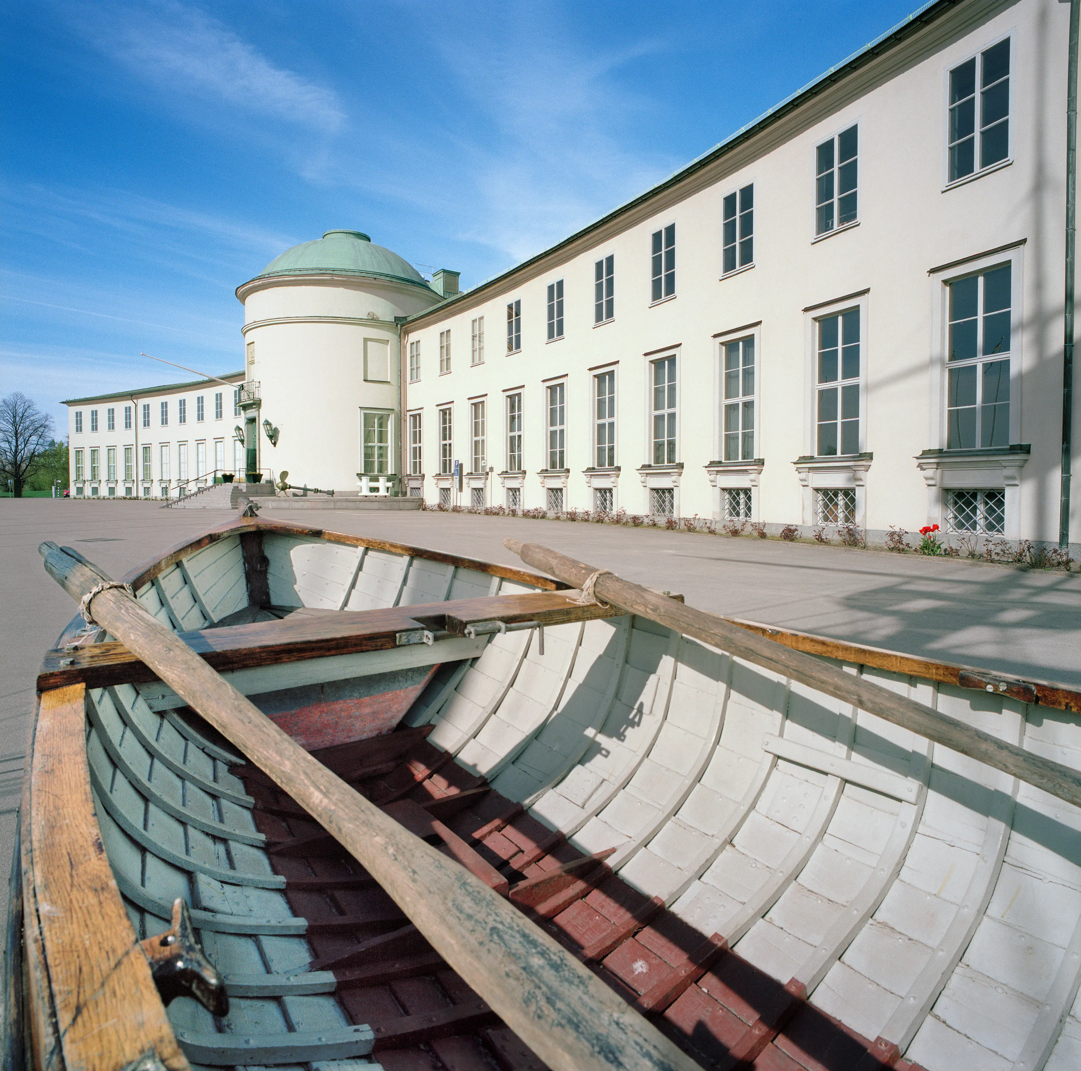 Sjöhistoriska museets entréfasad. En stor trä-eka ligger på gårdsplanen framför bygganden.