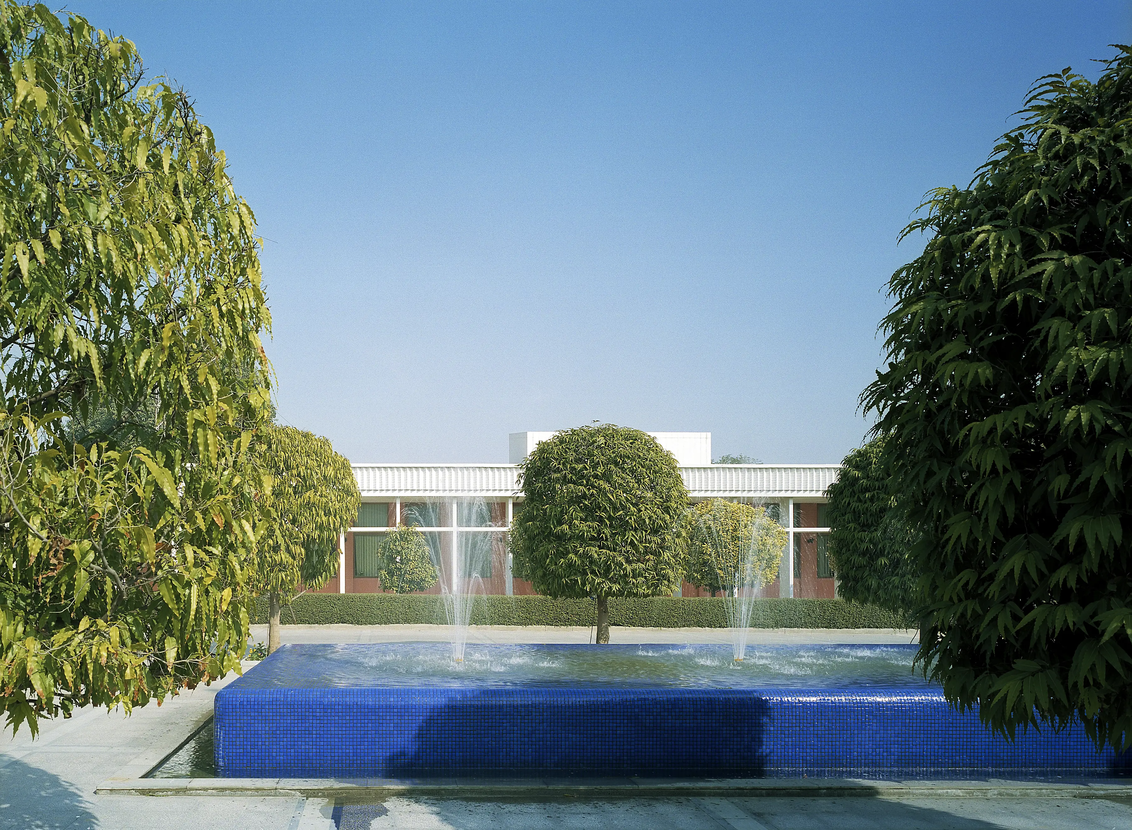 Fontänen på ambassadens gård i New Delhi. Bassängen är klädd i blå mosaik, och inramad av formklippta träd.