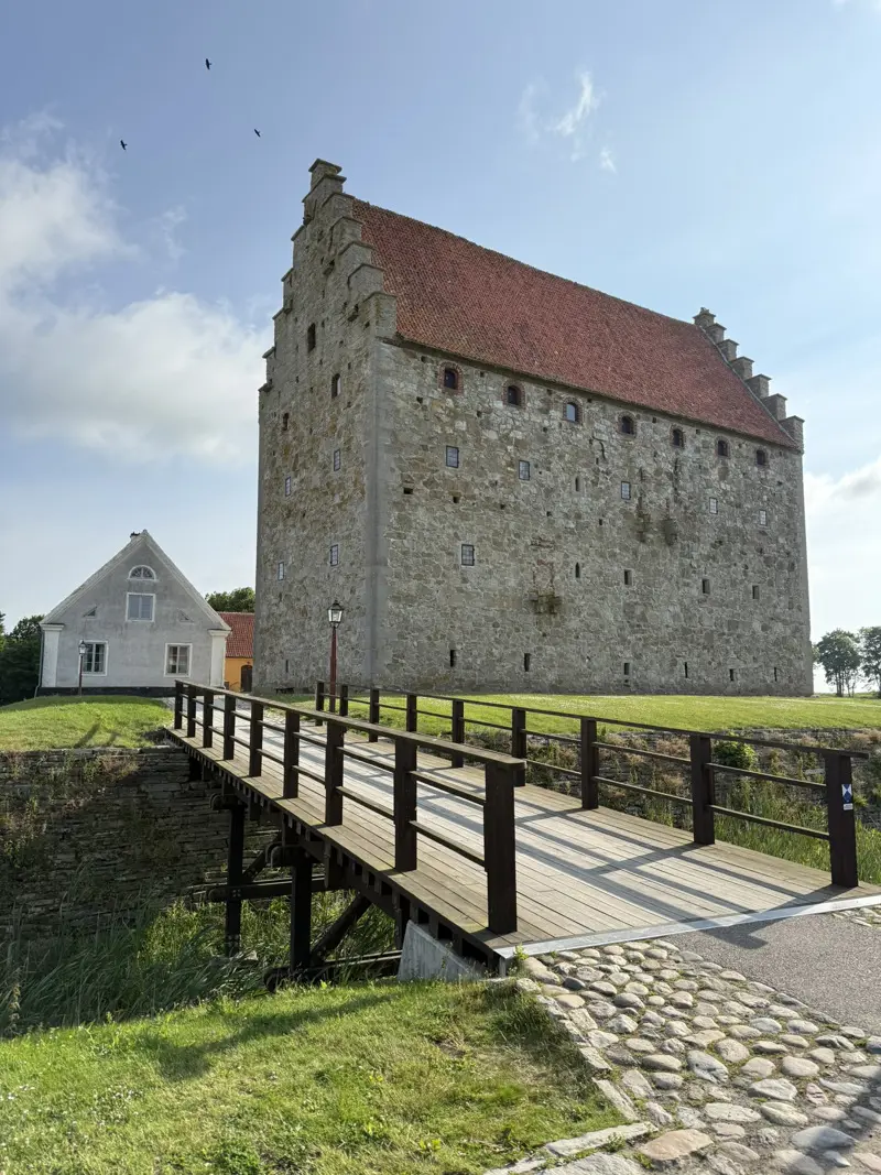 Stenborgen sedd från bron som går över vallgraven. Blå himmel med fåglar.