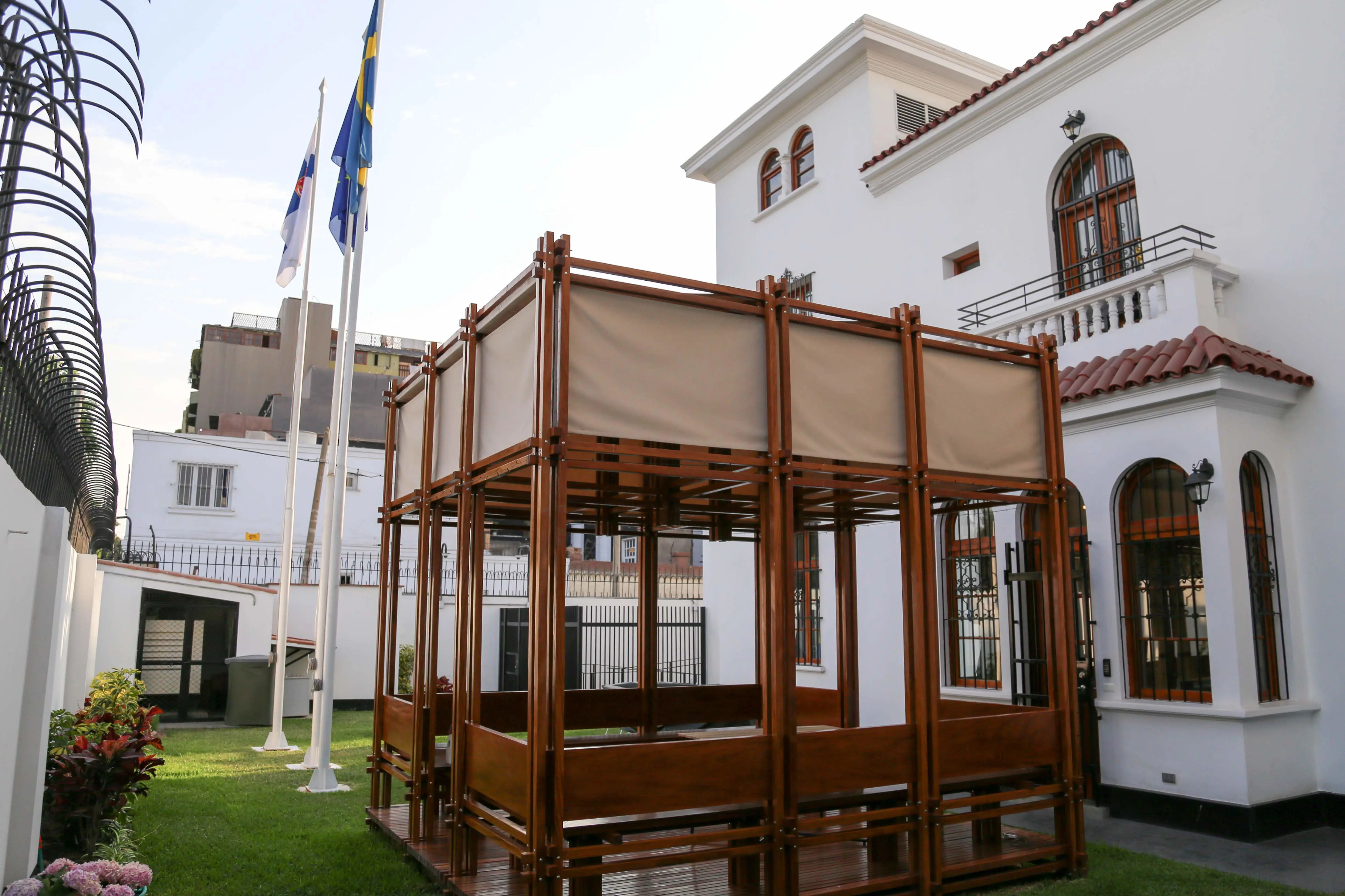 Ambassaden i Lima. Trädgården med pergola och flaggstänger med Sveriges flagga, Finlands flagga och EU-flaggan.